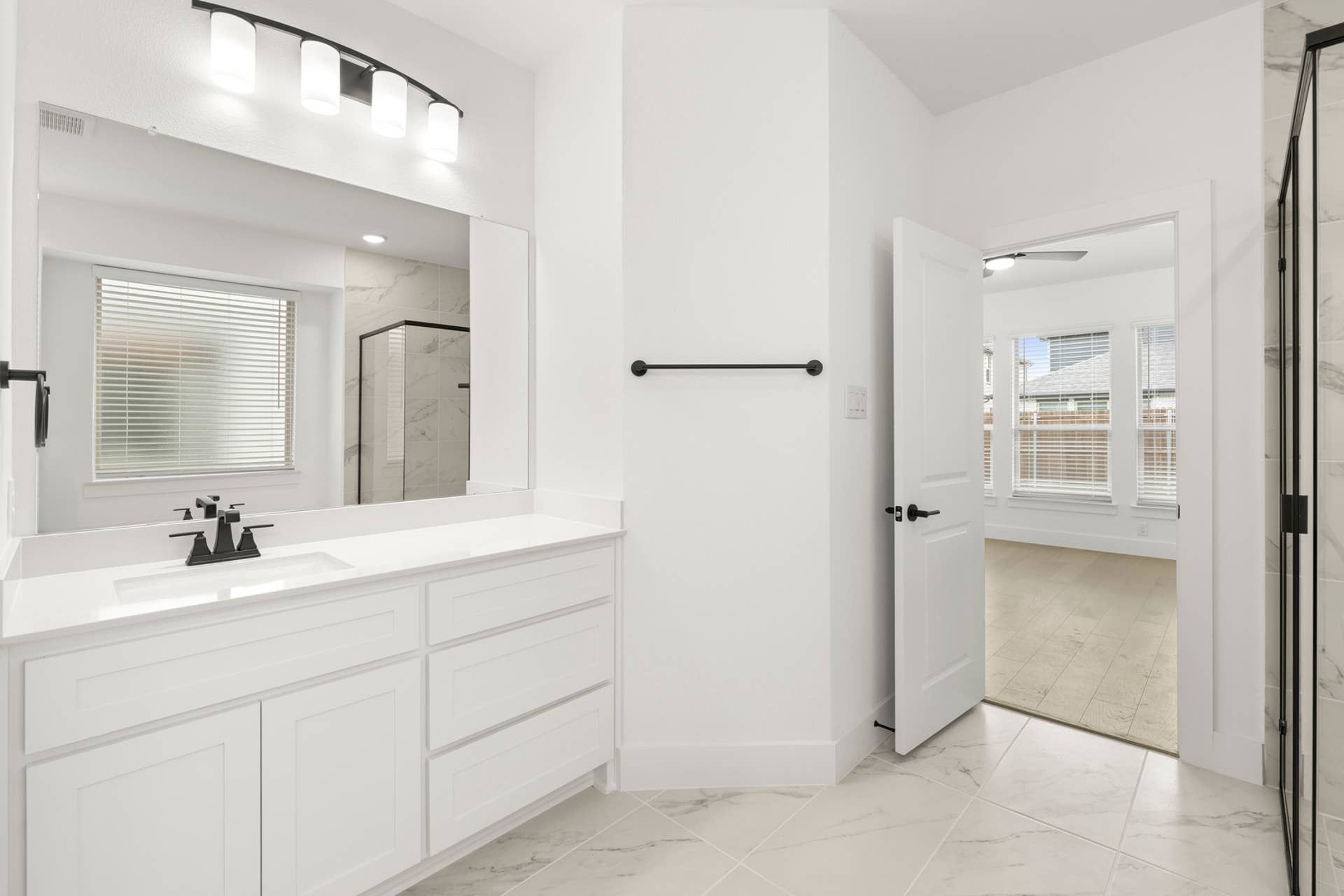 Modern bathroom with white vanity, large mirror, and glass-enclosed shower.