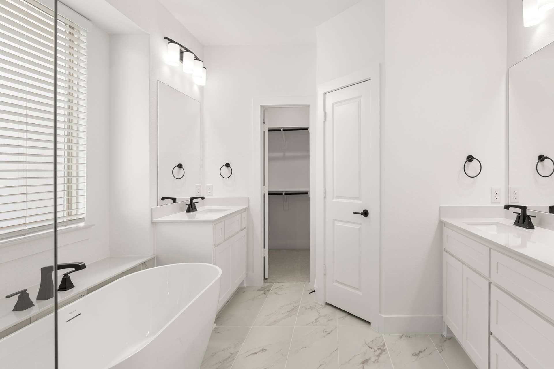 Modern bathroom with freestanding tub, dual vanities, and large mirrors.