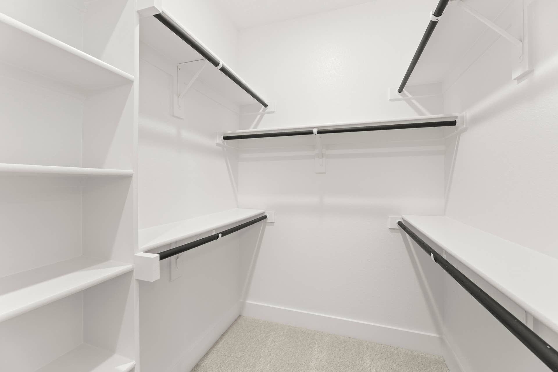 Spacious walk-in closet with white shelving and hanging rods.