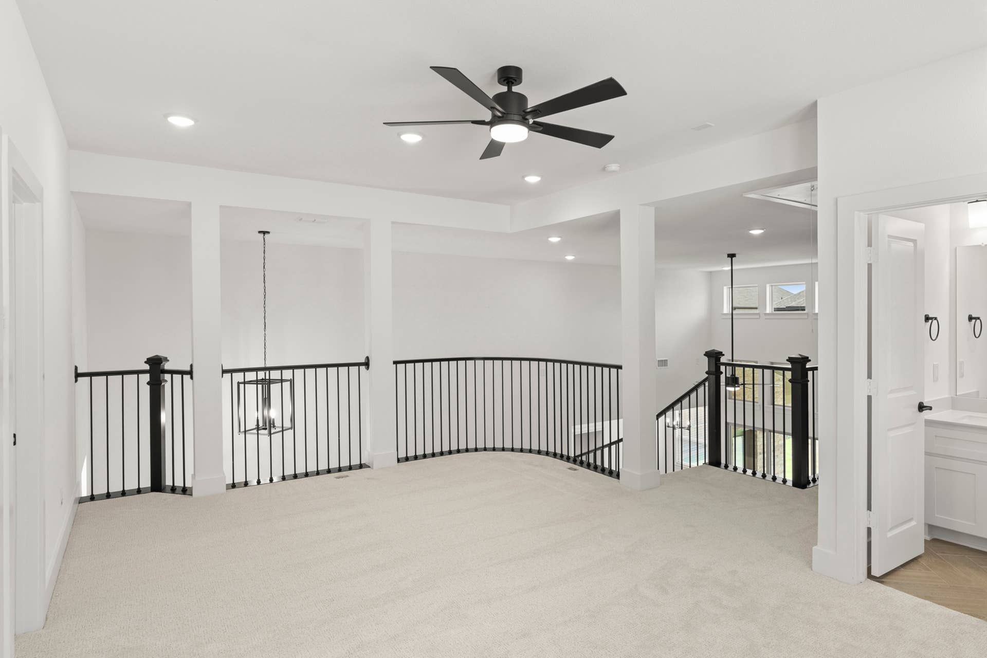 Spacious loft area with modern ceiling fan and black railing accents.
