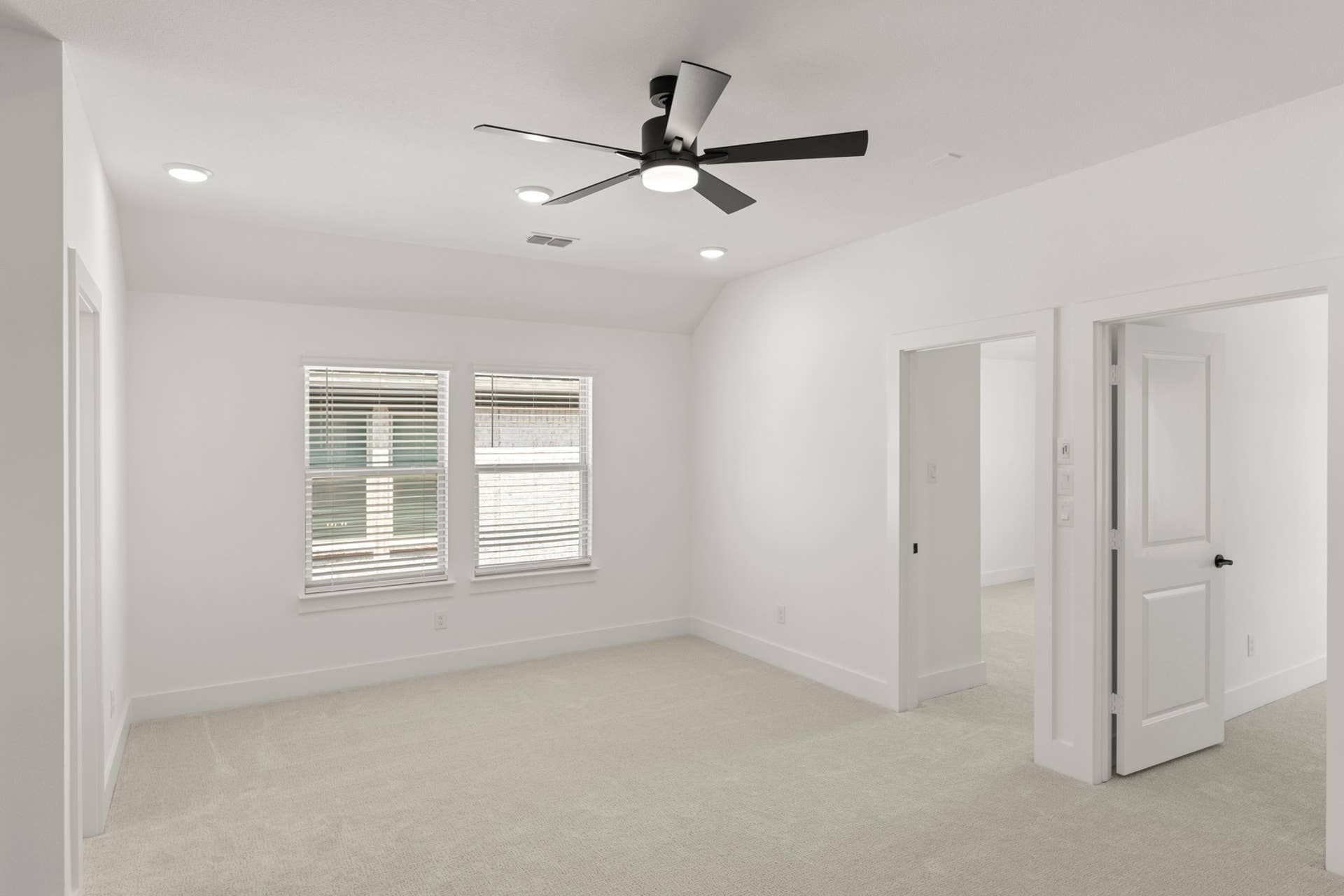 Spacious, bright interior room with ceiling fan and carpet flooring.