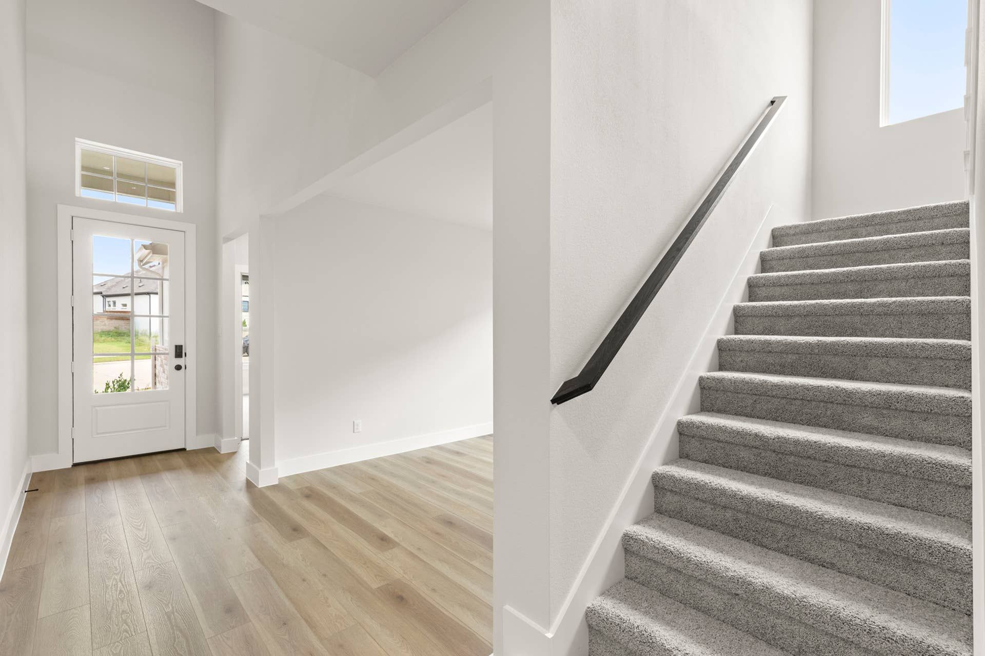 Bright entryway with hardwood floors and carpeted staircase.