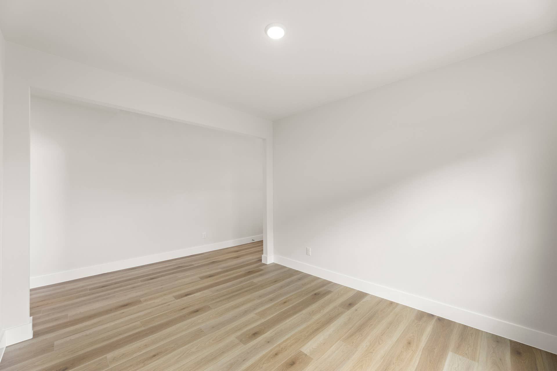 Minimalist dining room with light wood flooring and white walls.