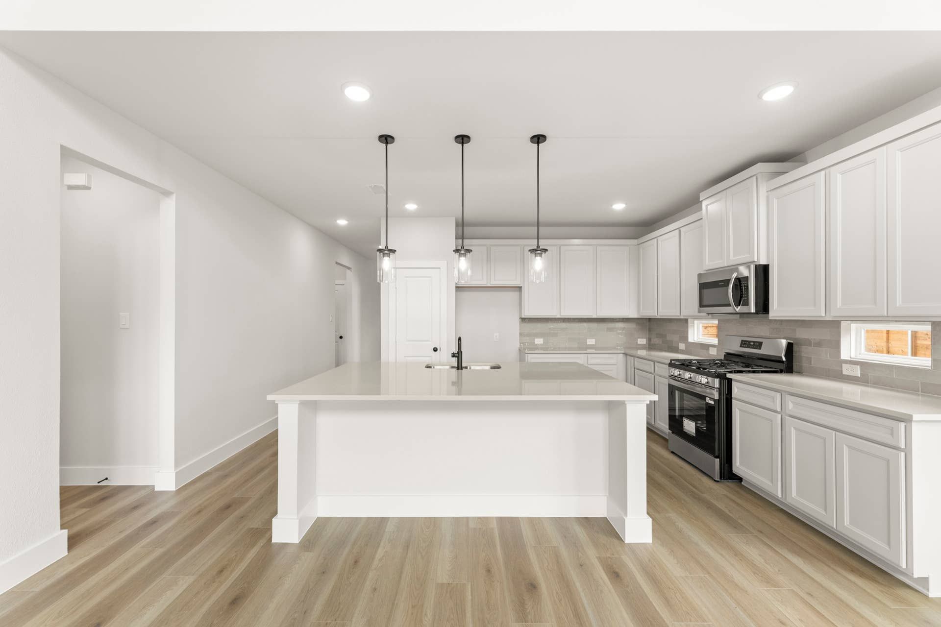 Modern kitchen with white cabinets, island, and pendant lighting.