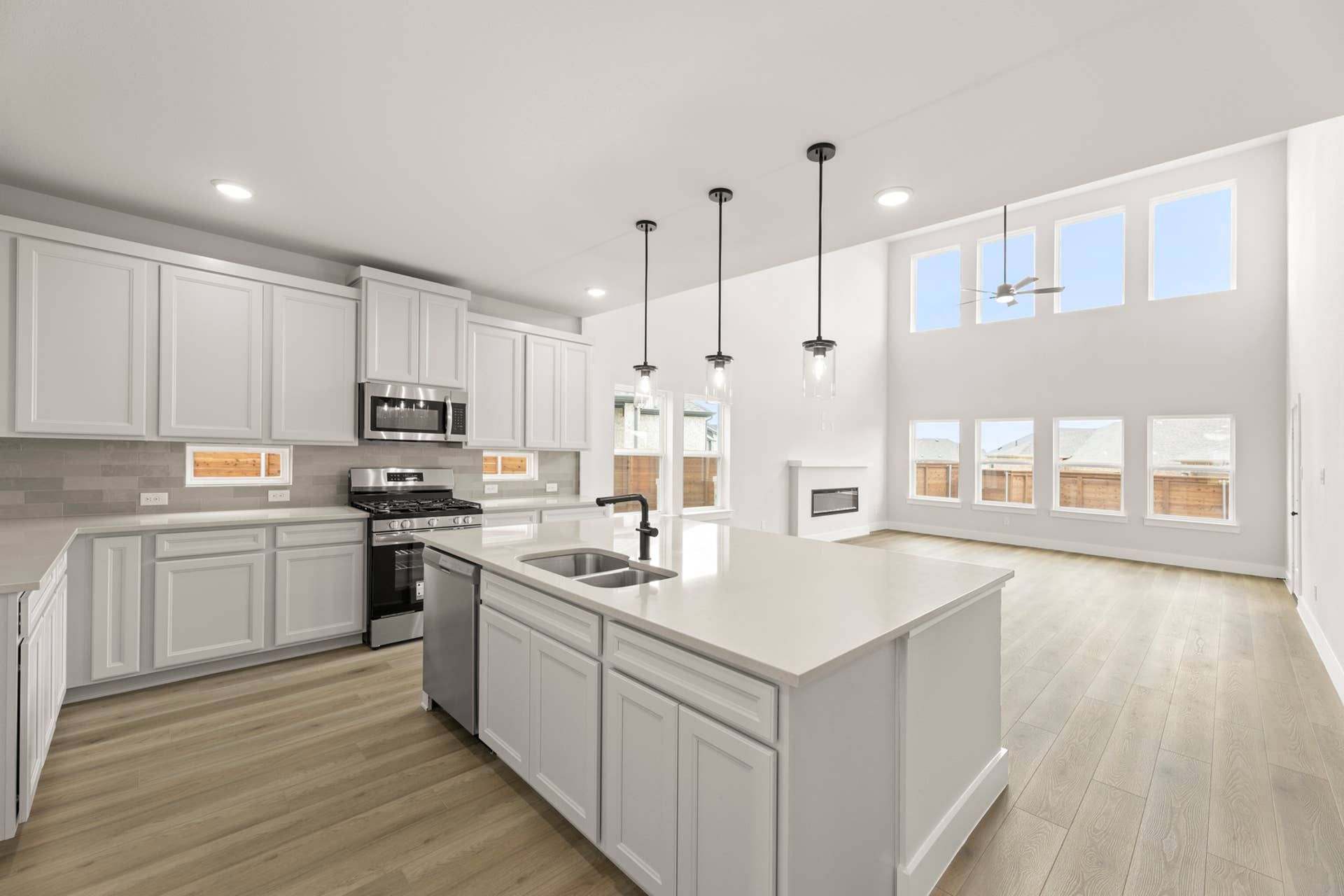 Modern kitchen with white cabinetry, large island, and pendant lighting.
