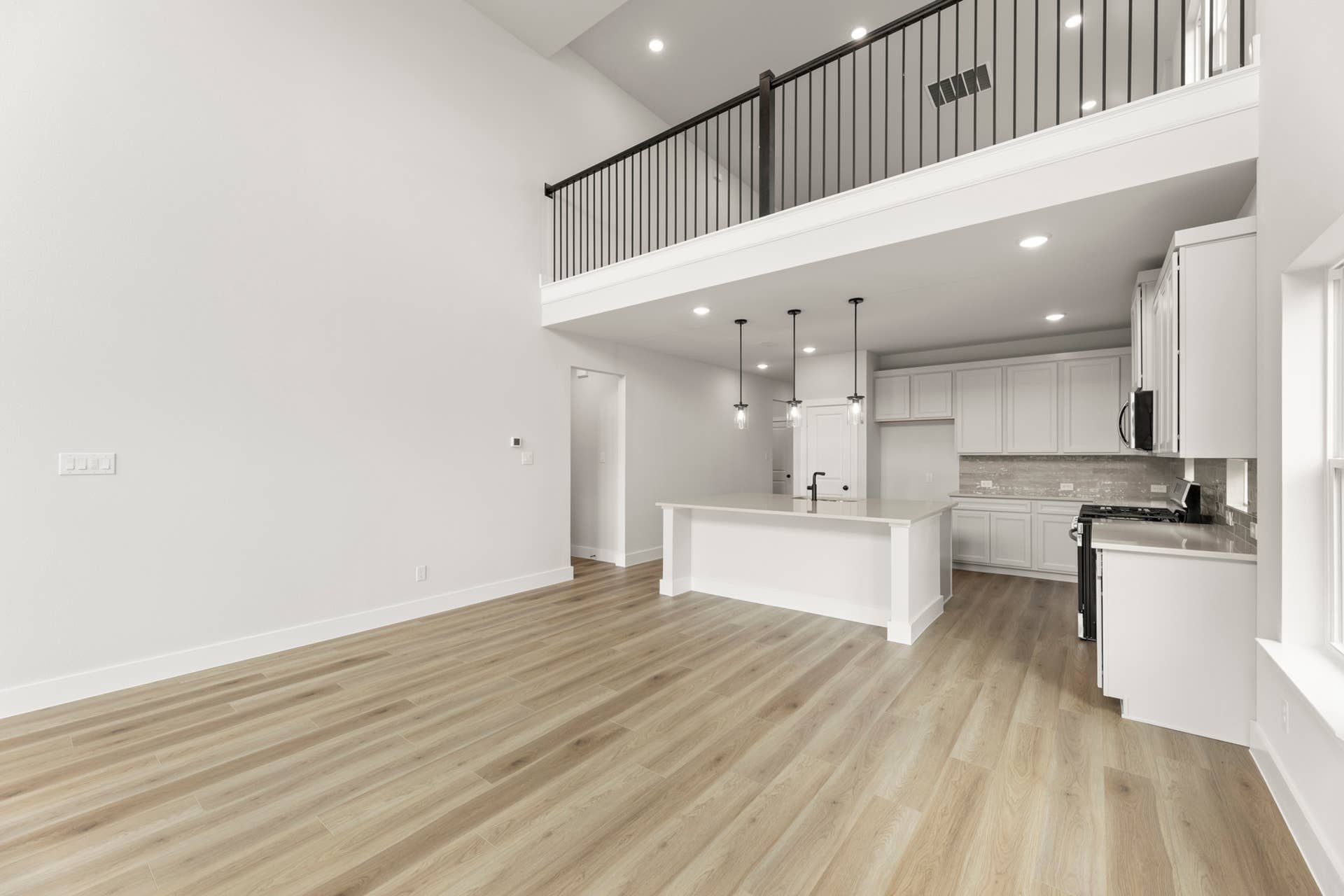 Modern kitchen interior with high ceiling, balcony, and hardwood flooring.