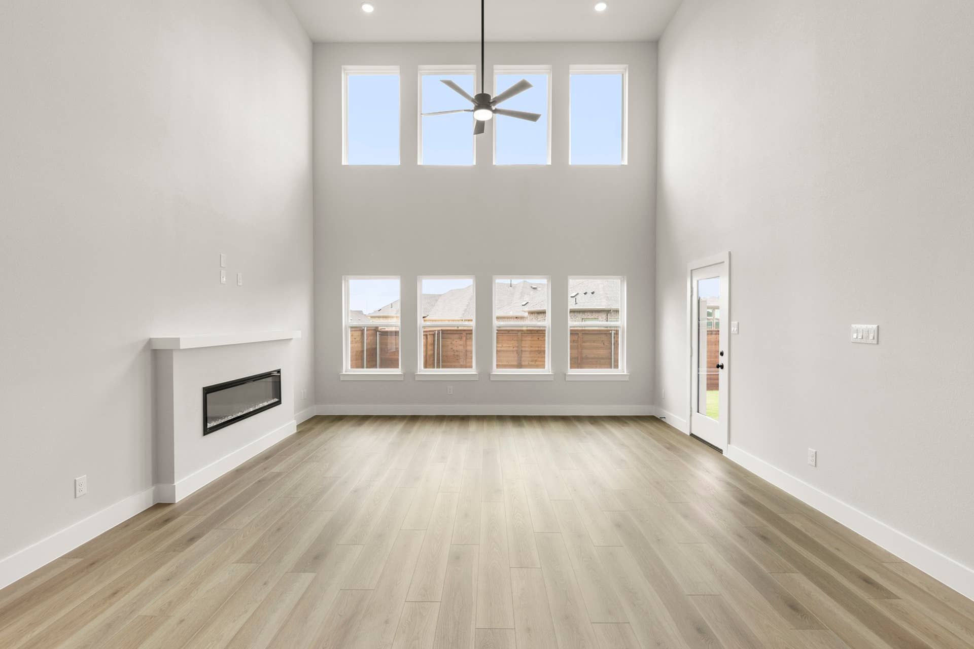 Spacious living room with high ceilings, large windows, and modern fireplace.