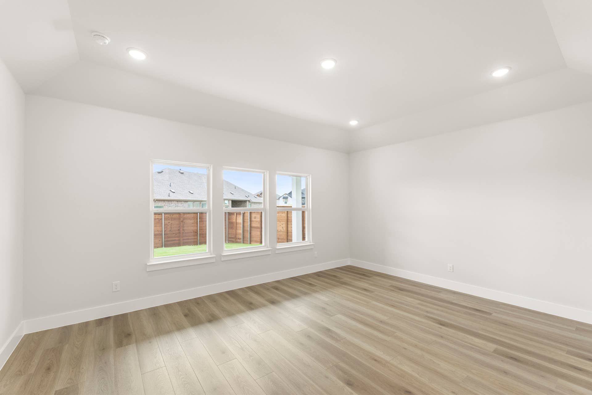 Spacious bright room with wooden flooring and large windows.