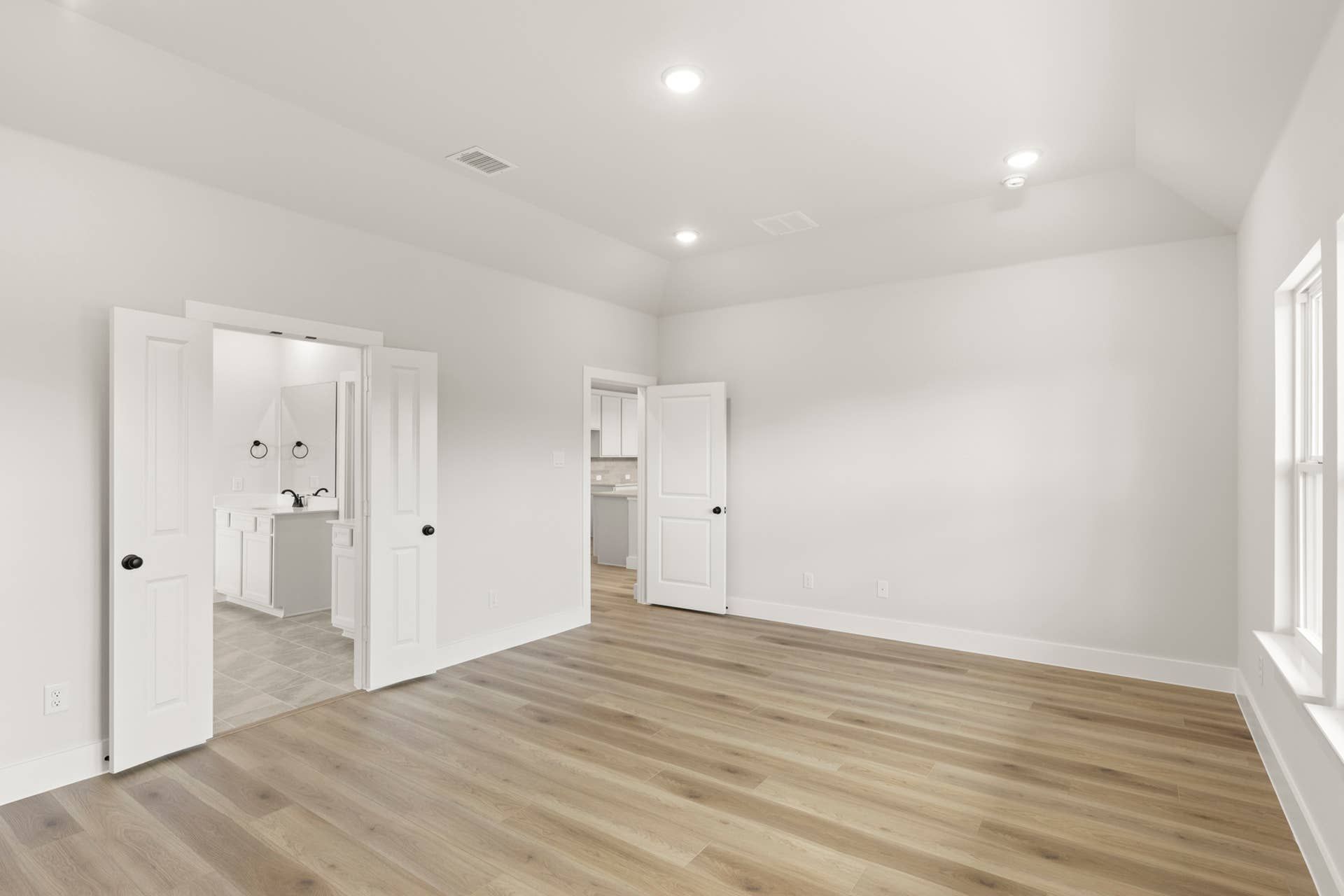 Spacious primary bedroom with wood flooring and en-suite bathroom access.