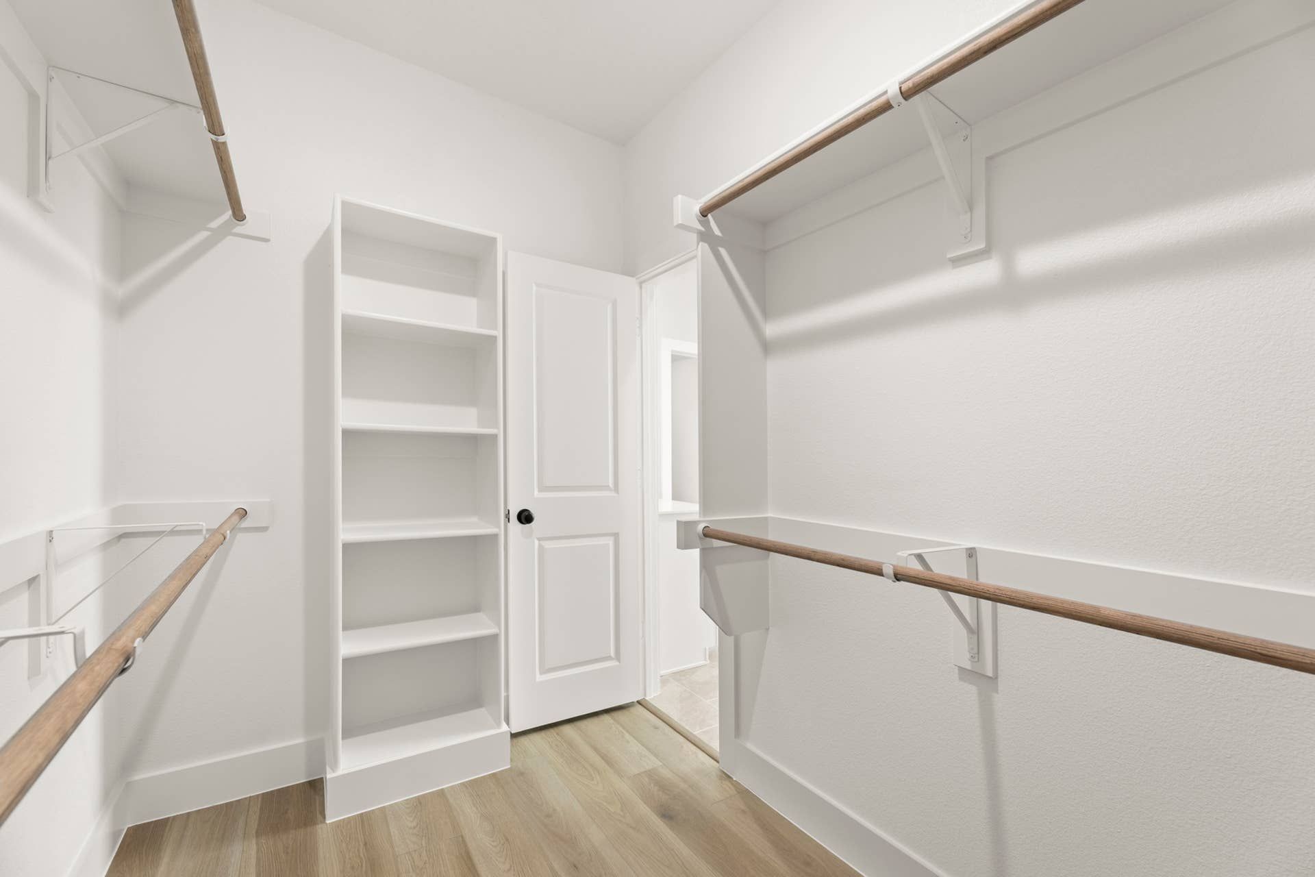 Spacious walk-in closet with built-in shelves and wooden rods.