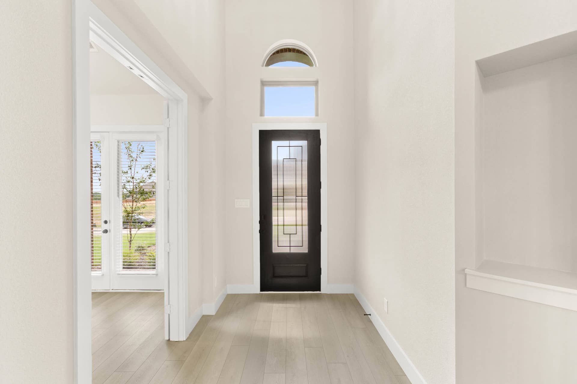 Bright entryway with dark front door and transom window.