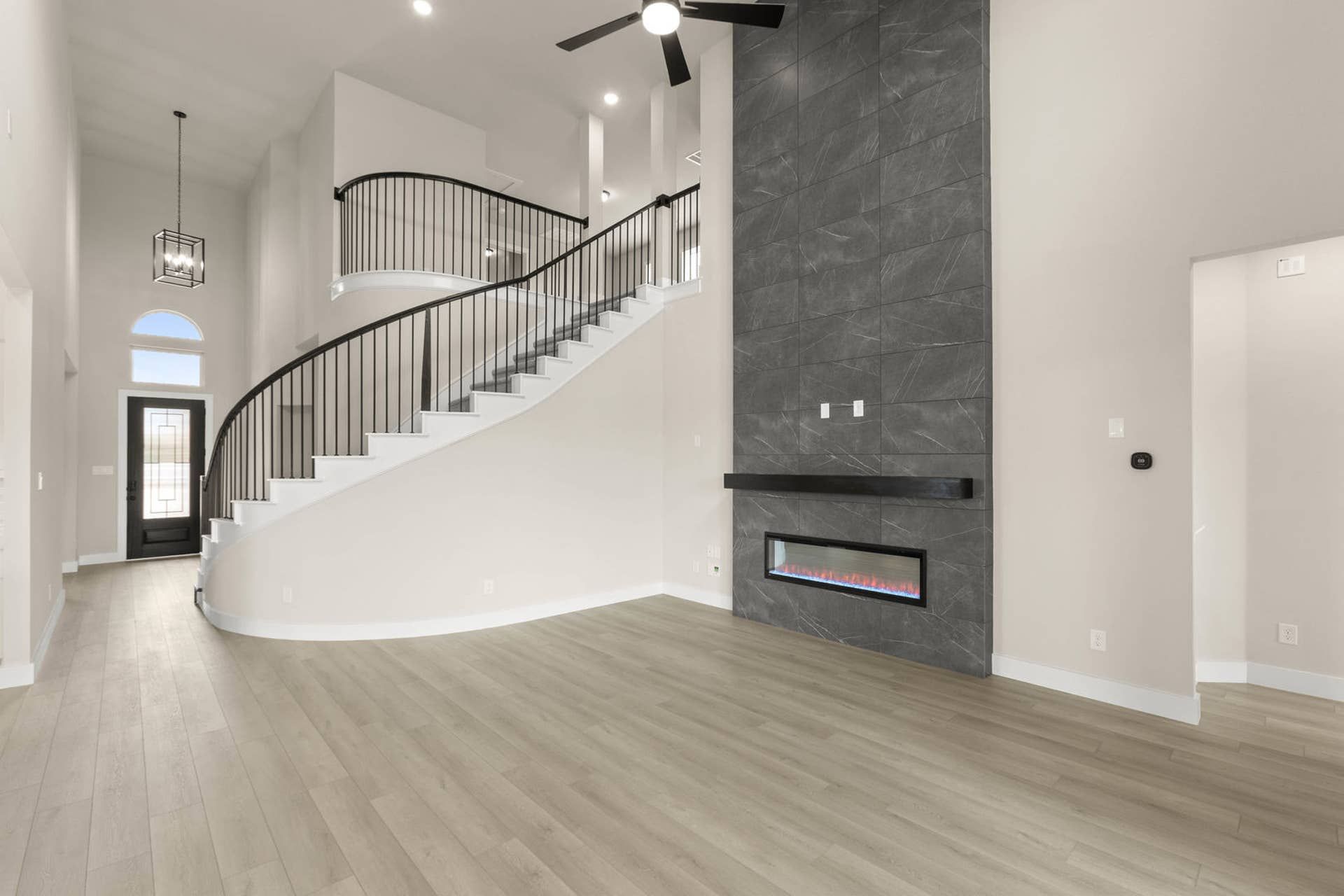 Spacious living room with modern staircase and sleek fireplace accent wall.