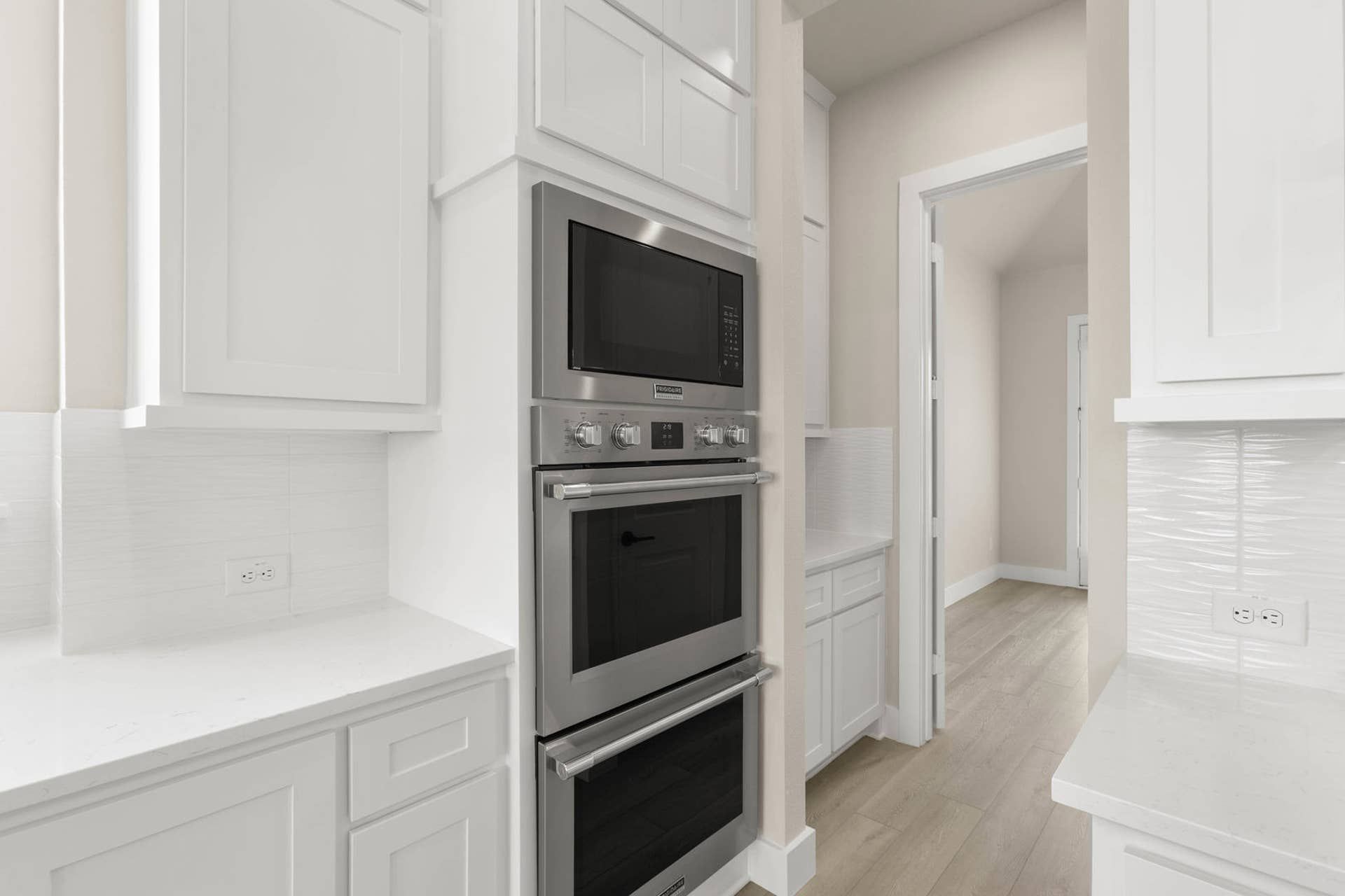 Modern kitchen with stainless steel appliances and white cabinetry.