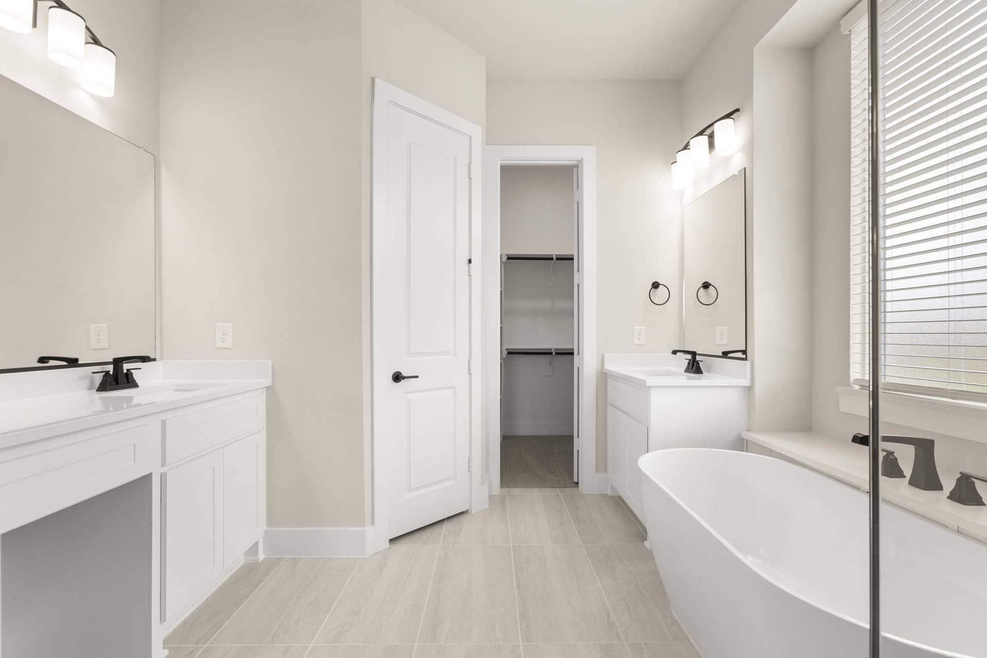 Spacious bathroom with dual vanities, freestanding tub, and walk-in closet.