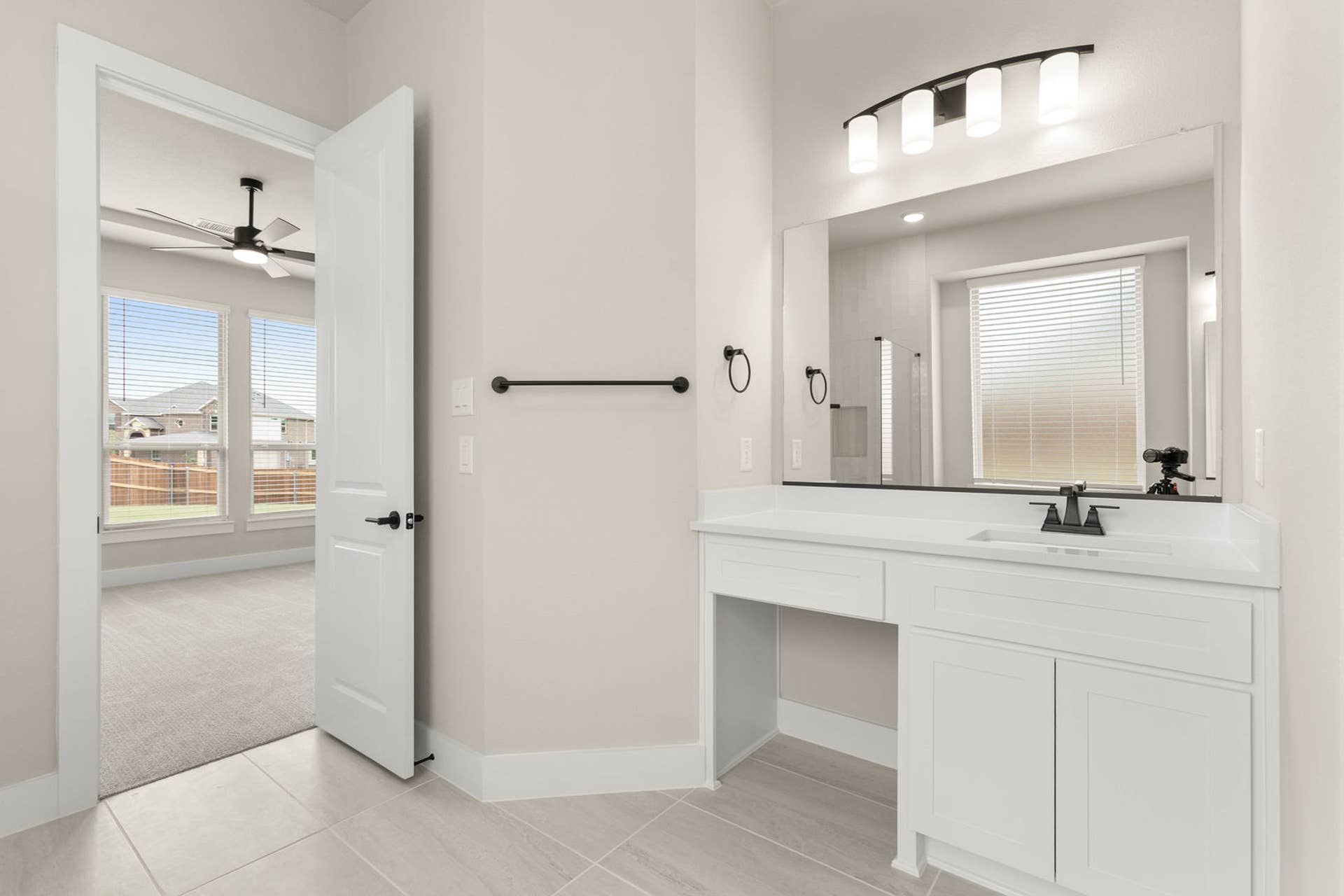 Modern bathroom with sleek vanity, large mirror, and adjacent bedroom view.