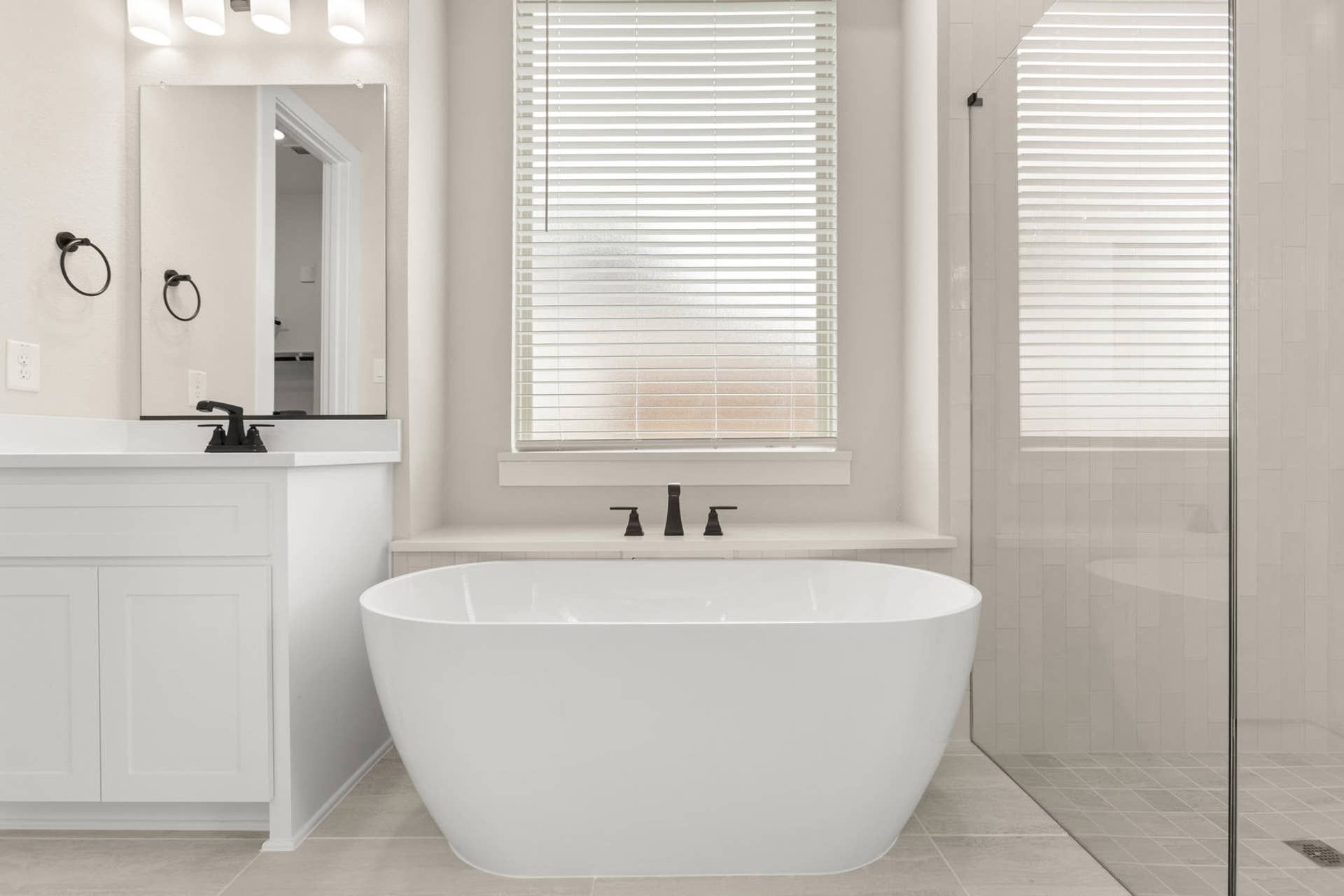 Elegant bathroom with freestanding tub, modern fixtures, and glass shower enclosure.