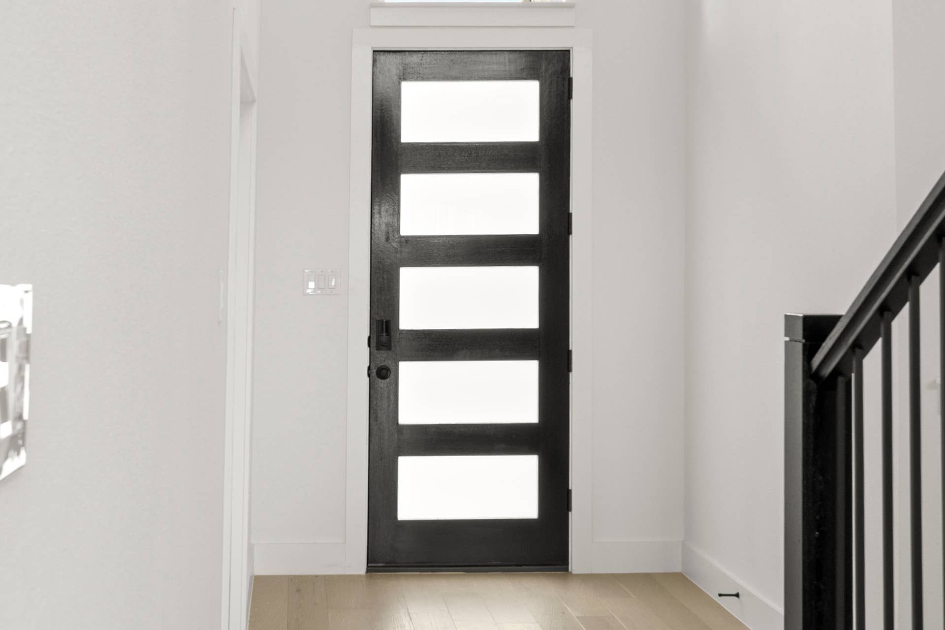 Modern entryway with sleek black door and frosted glass panels.