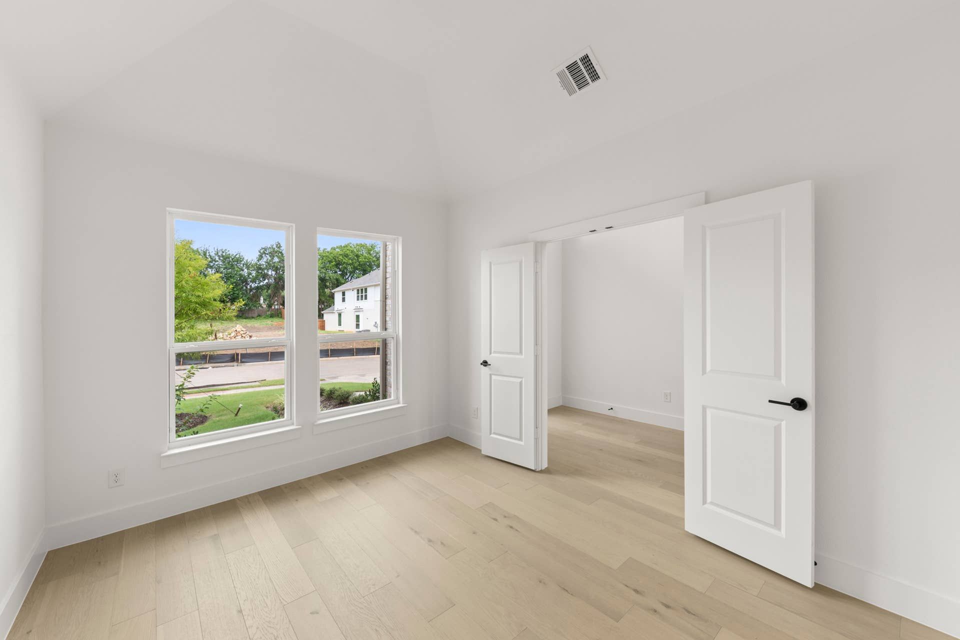 Bright dining room with hardwood floors and double doors to adjacent room.