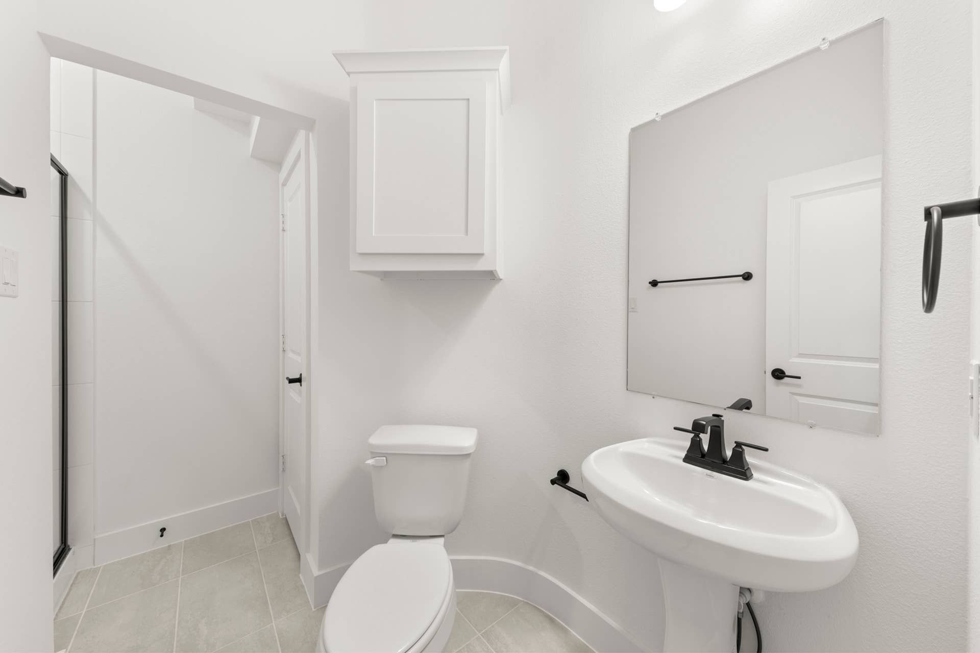 Modern white bathroom with pedestal sink and frameless mirror.