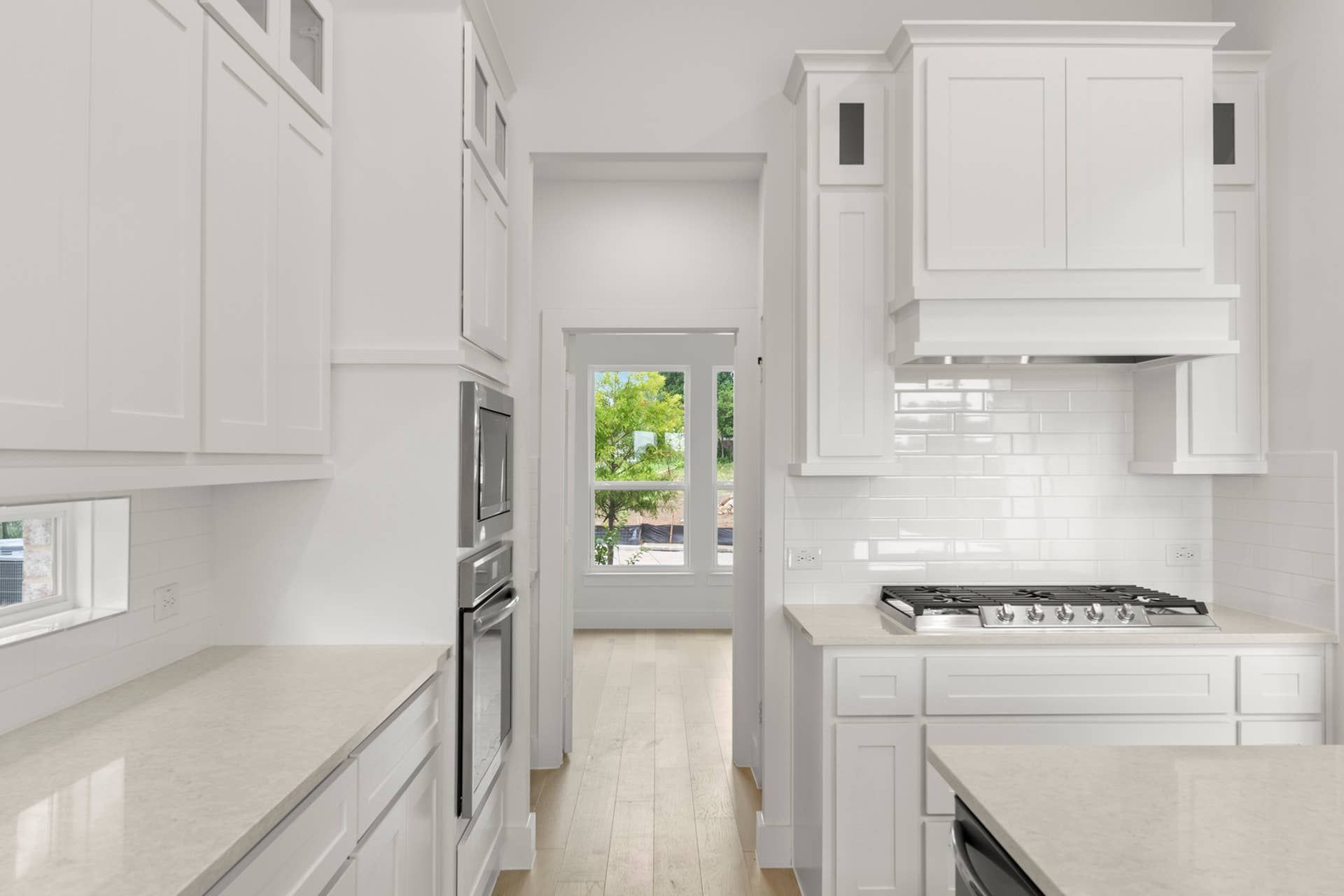 Bright modern kitchen with white cabinetry and stainless steel appliances.
