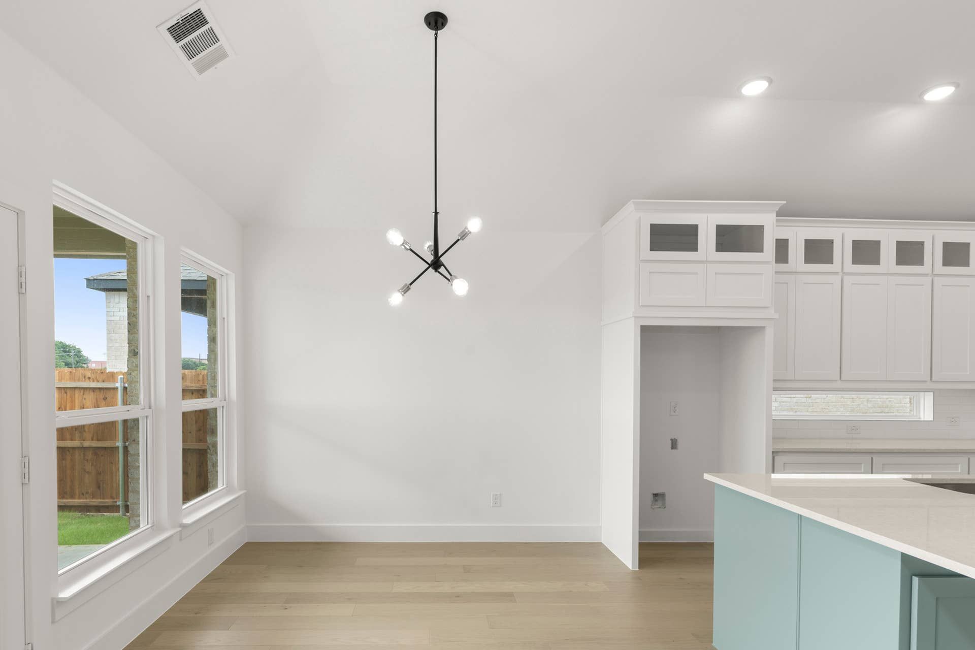 Spacious kitchen nook with modern pendant light and large windows.