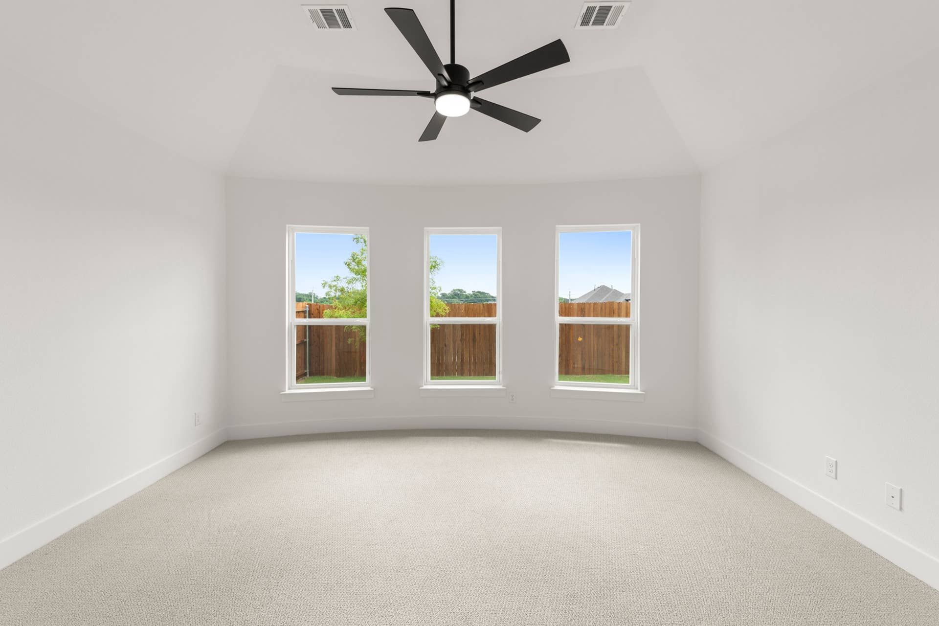 Bright room with three large windows and ceiling fan.