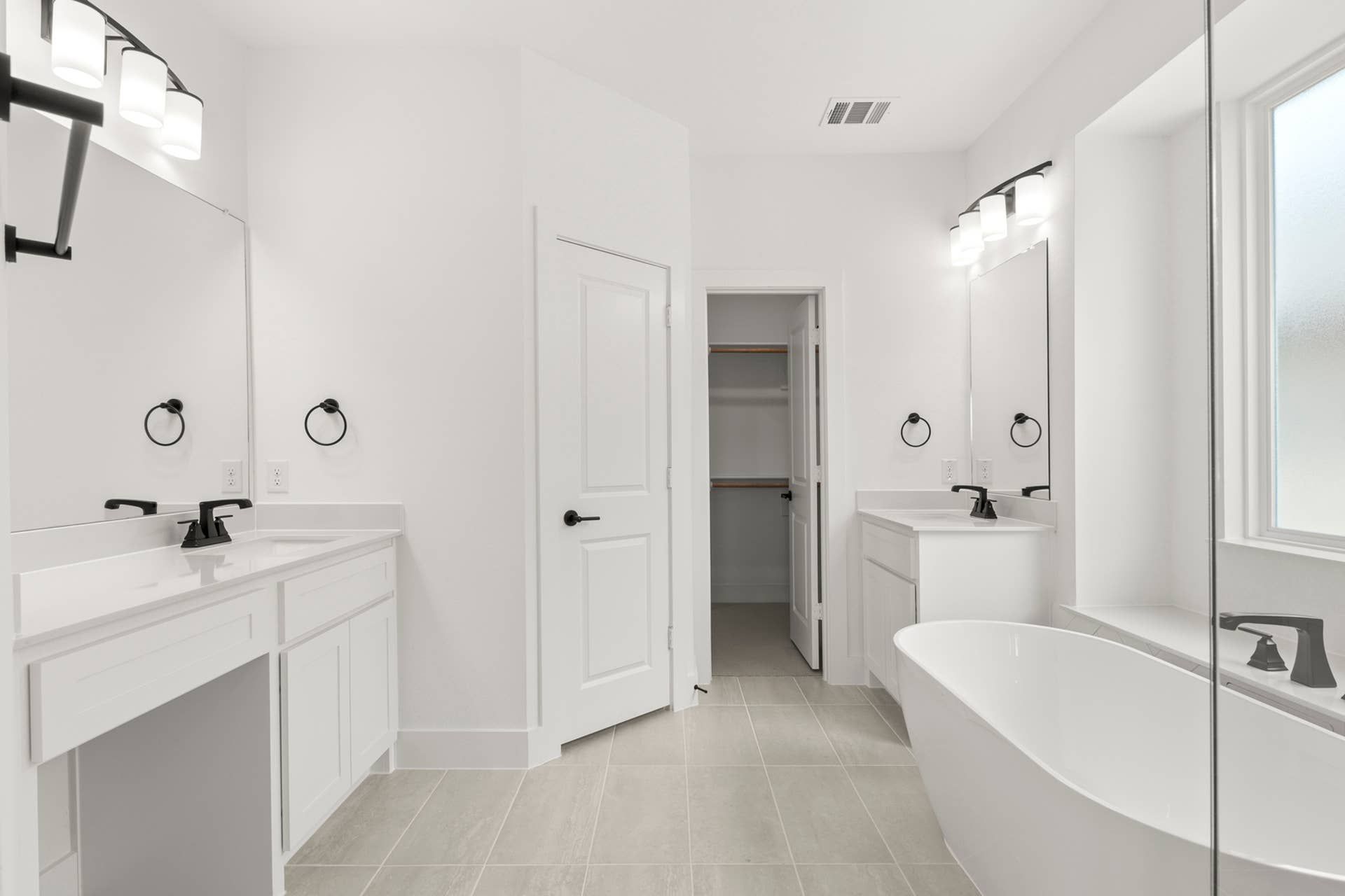 Modern white bathroom with double vanity and freestanding bathtub.
