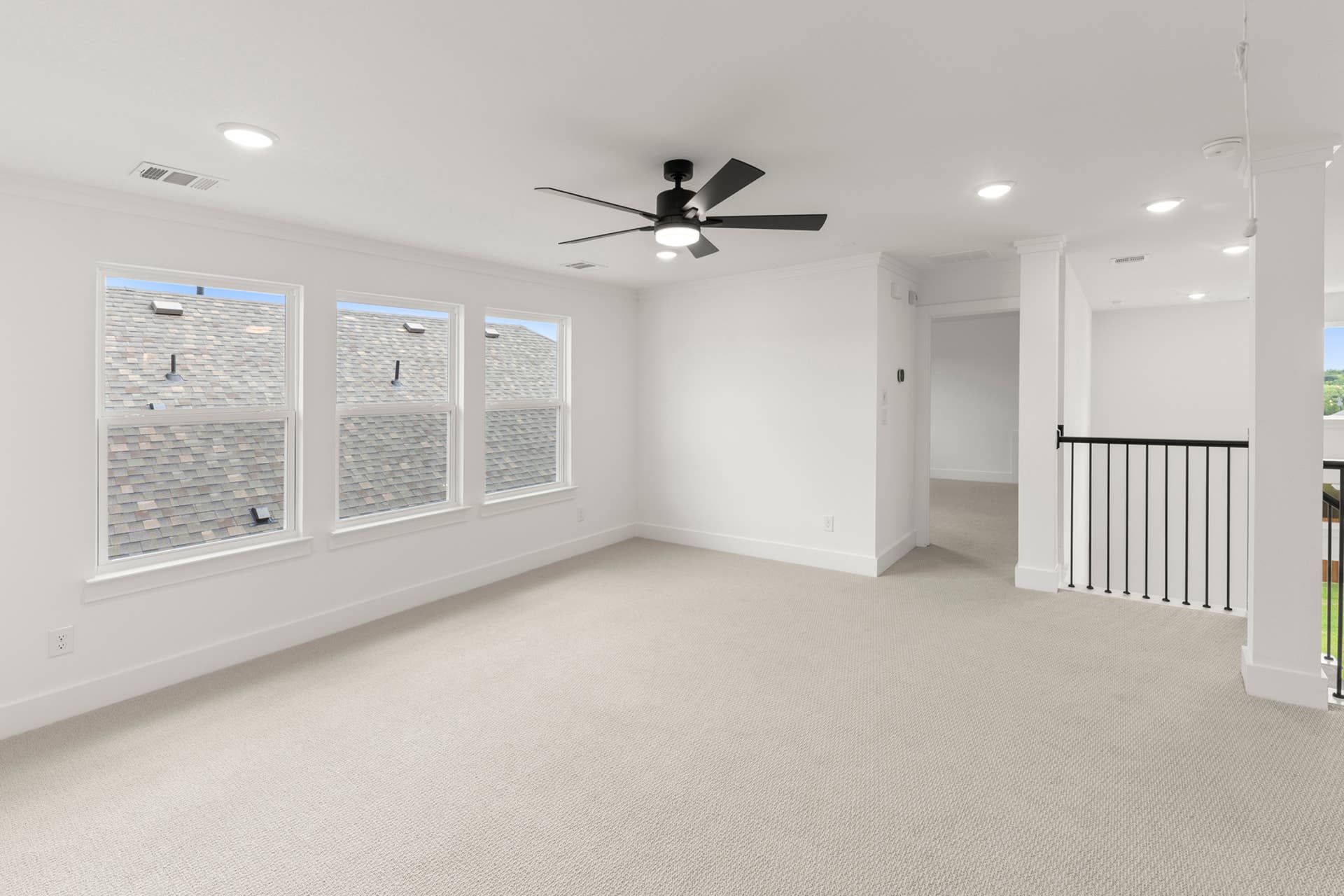 Spacious neutral-toned interior room with ceiling fan and multiple windows.