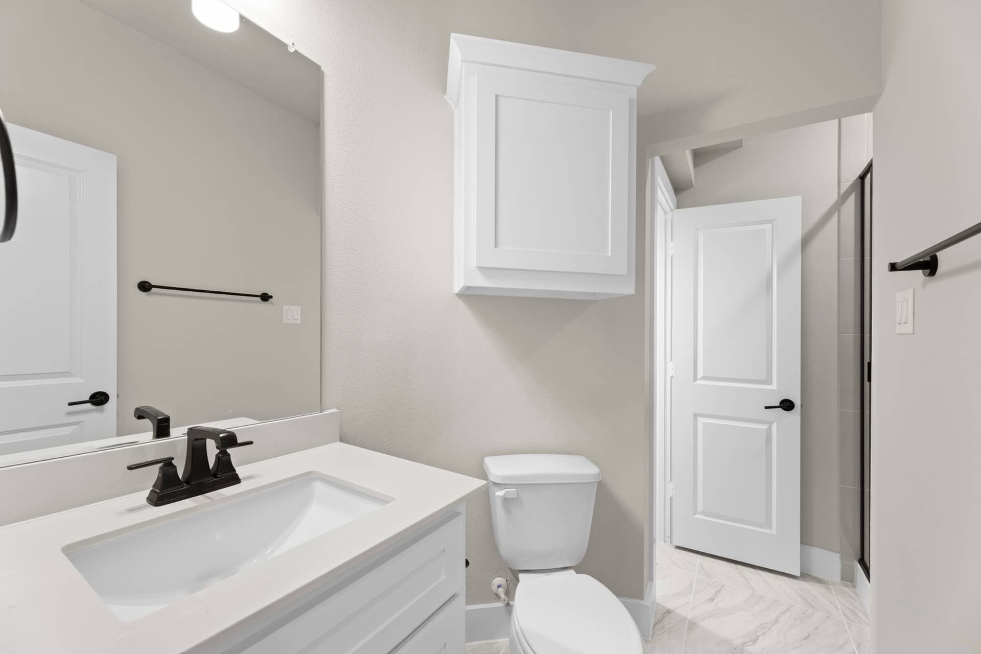 Modern bathroom with white vanity, mirror, and sleek black fixtures.