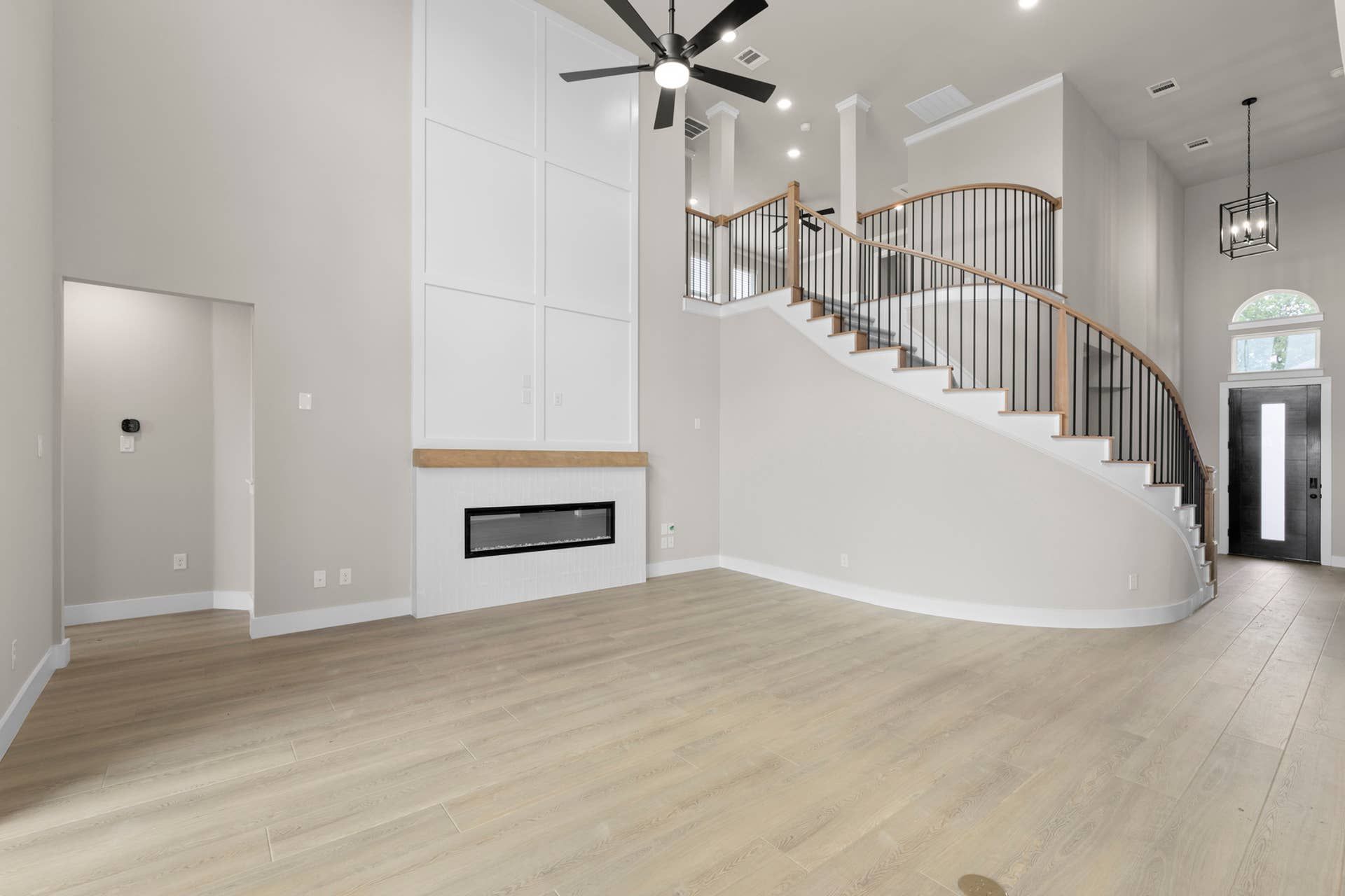 Spacious living room with modern fireplace and elegant spiral staircase.