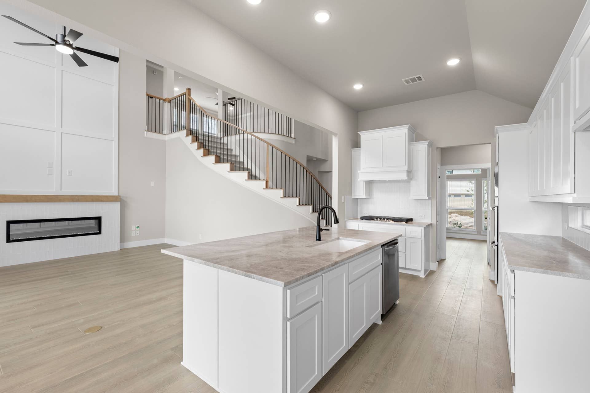 Modern kitchen with marble island, open layout, and elegant staircase.