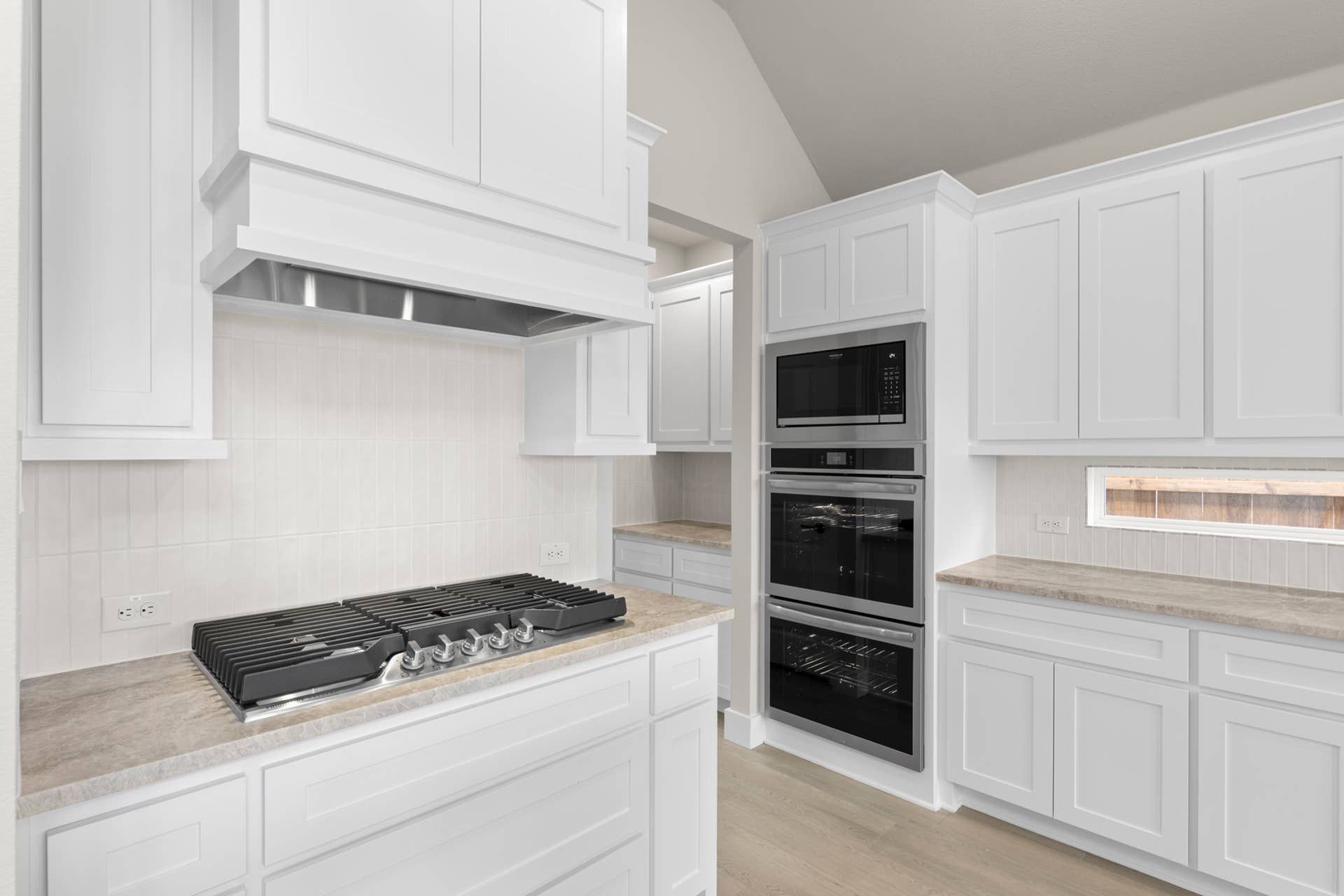 Modern kitchen with white cabinetry, built-in oven, and sleek cooktop.