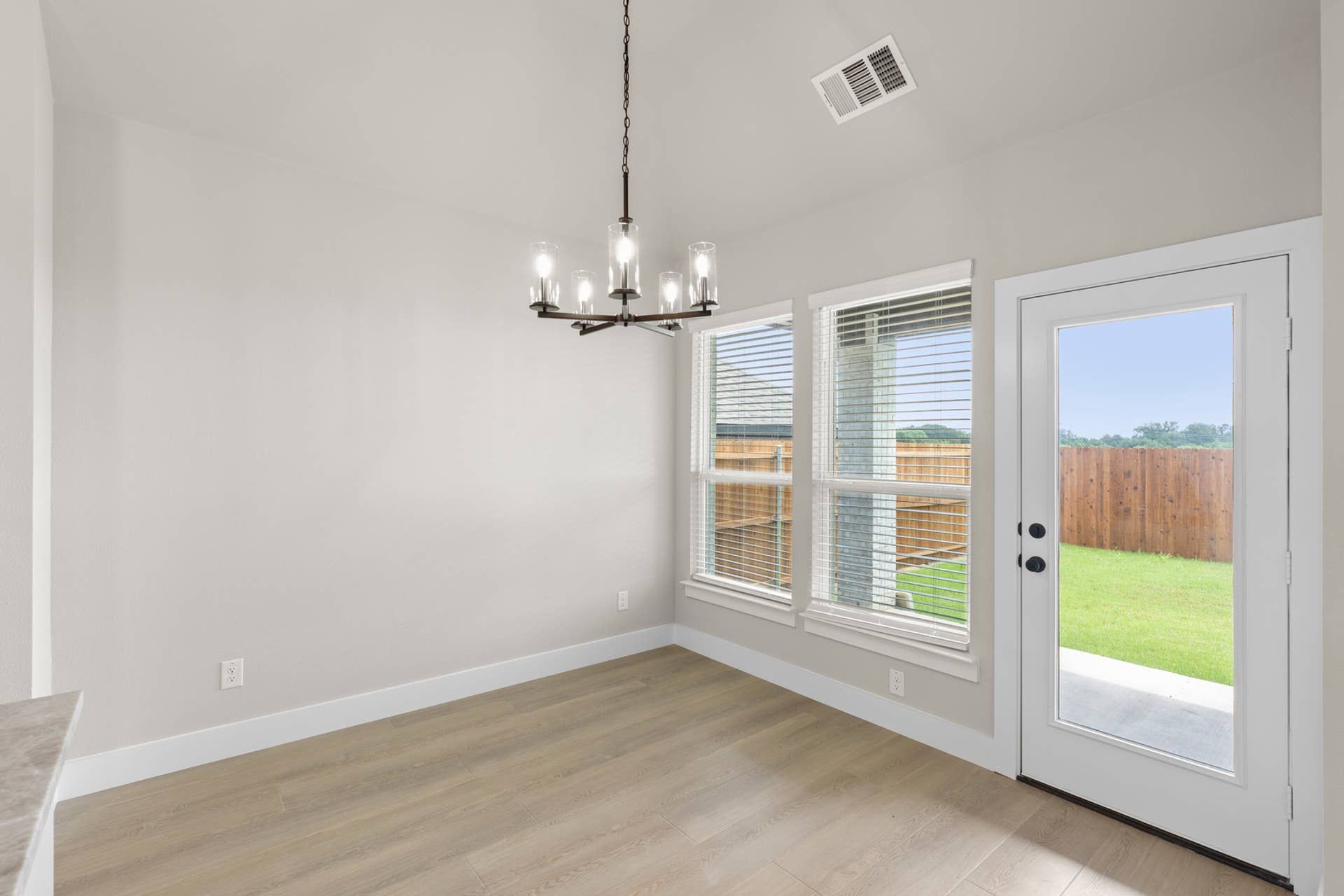 Bright interior nook with chandelier, large windows, and door to backyard.