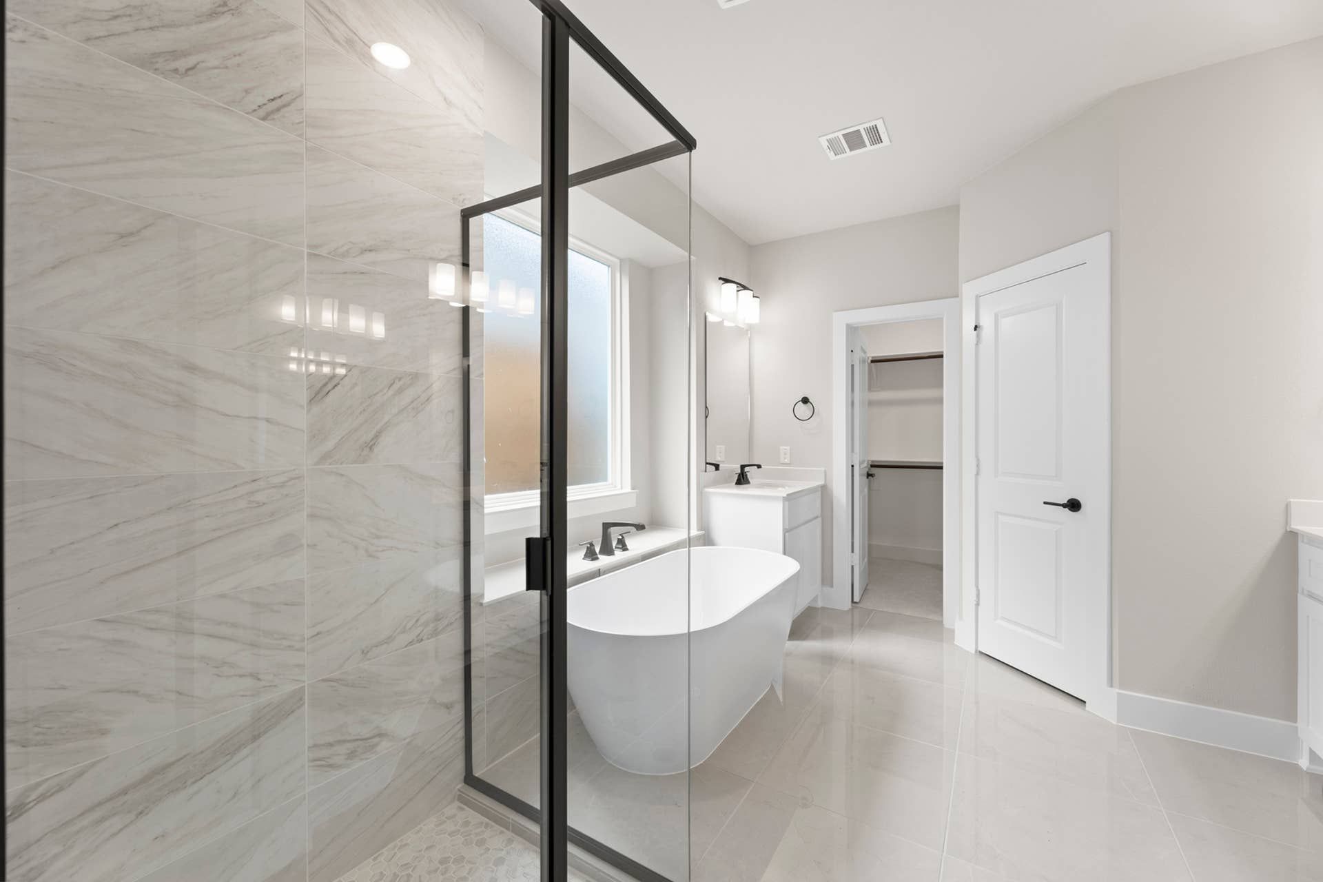 Modern bathroom with glass shower, freestanding tub, and spacious walk-in closet.