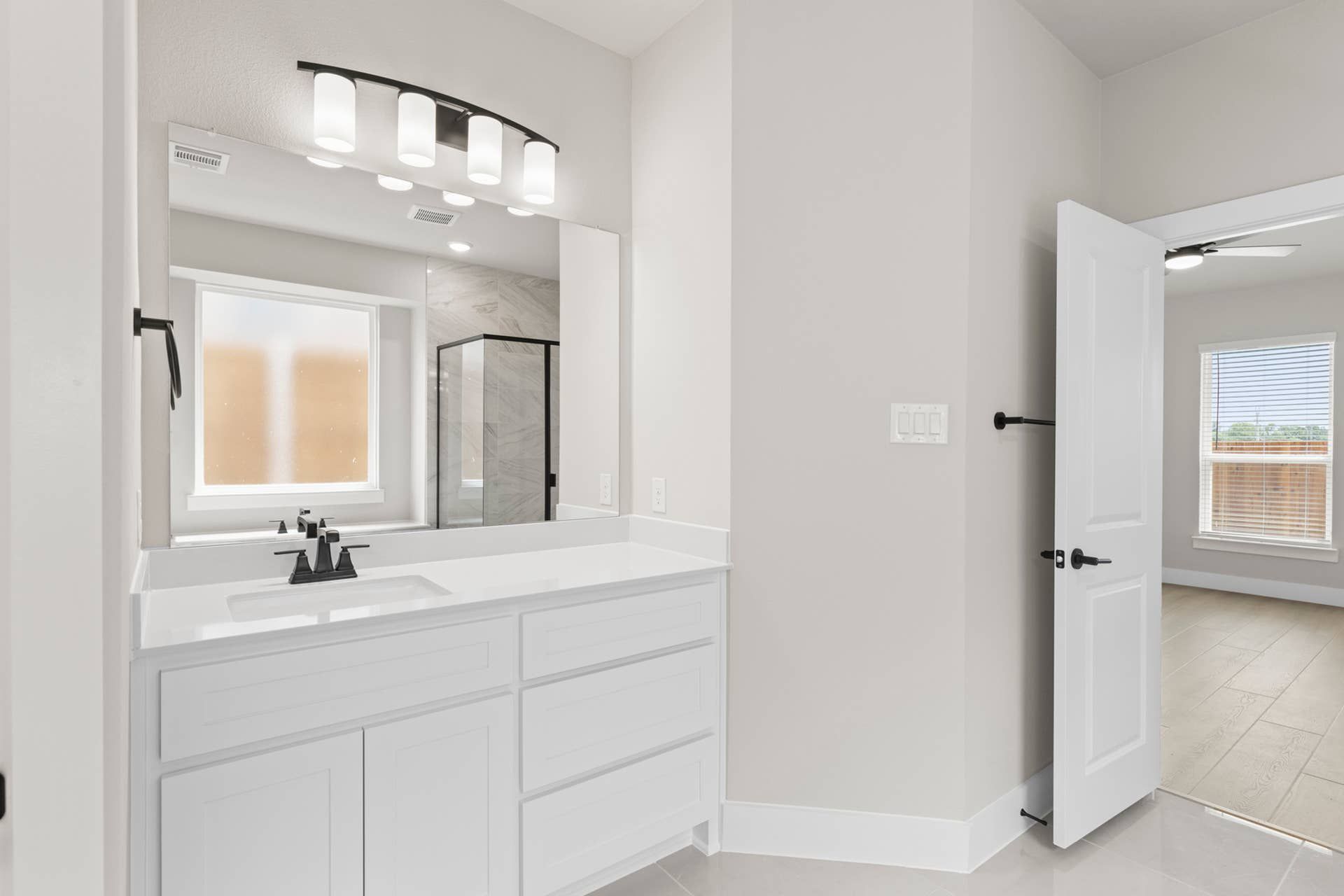 Modern bathroom with white vanity, large mirror, and glass-enclosed shower.
