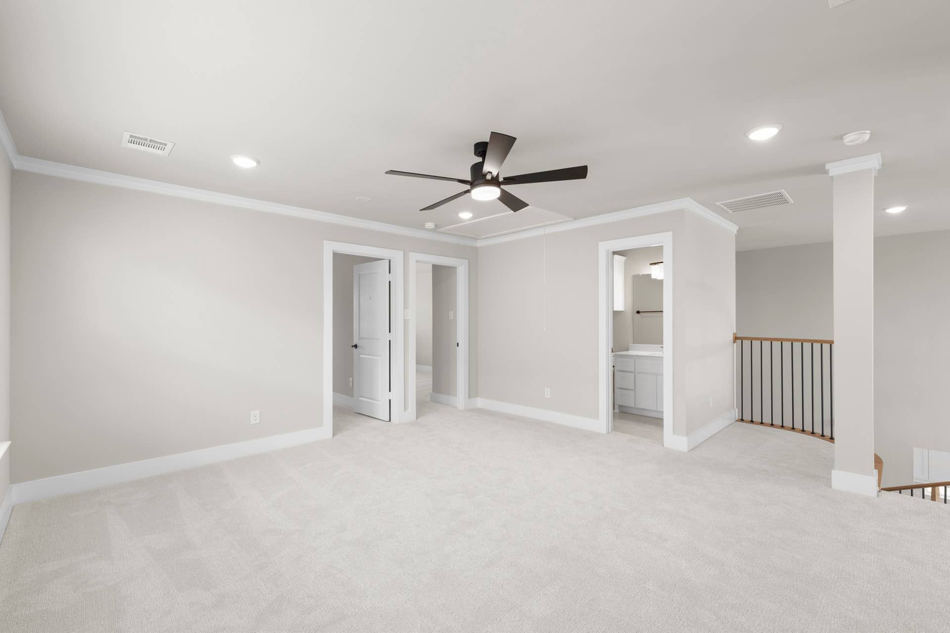 Spacious interior room with ceiling fan, neutral walls, and carpet flooring.
