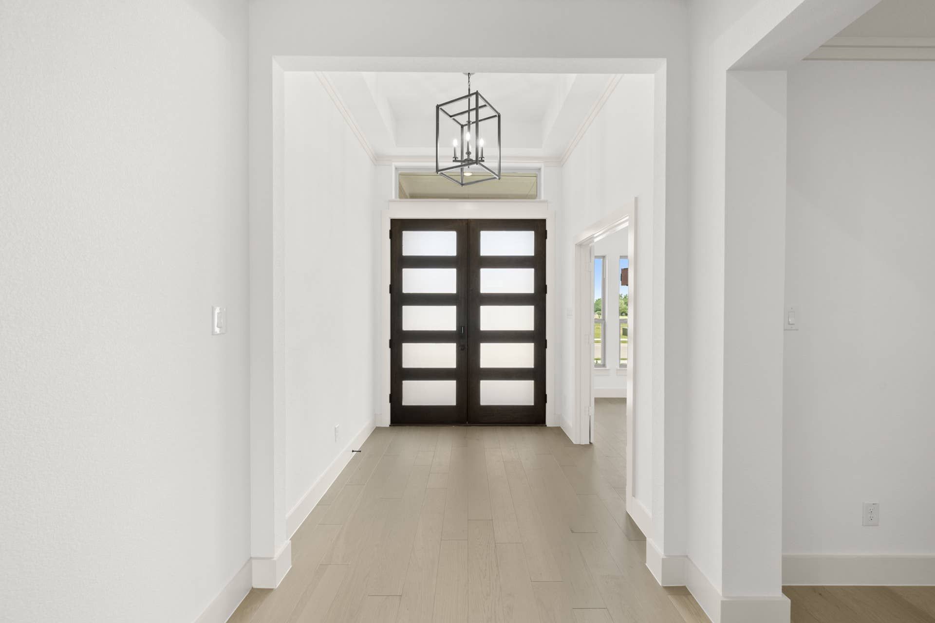 Modern entryway with glass-paneled double doors and geometric light fixture.