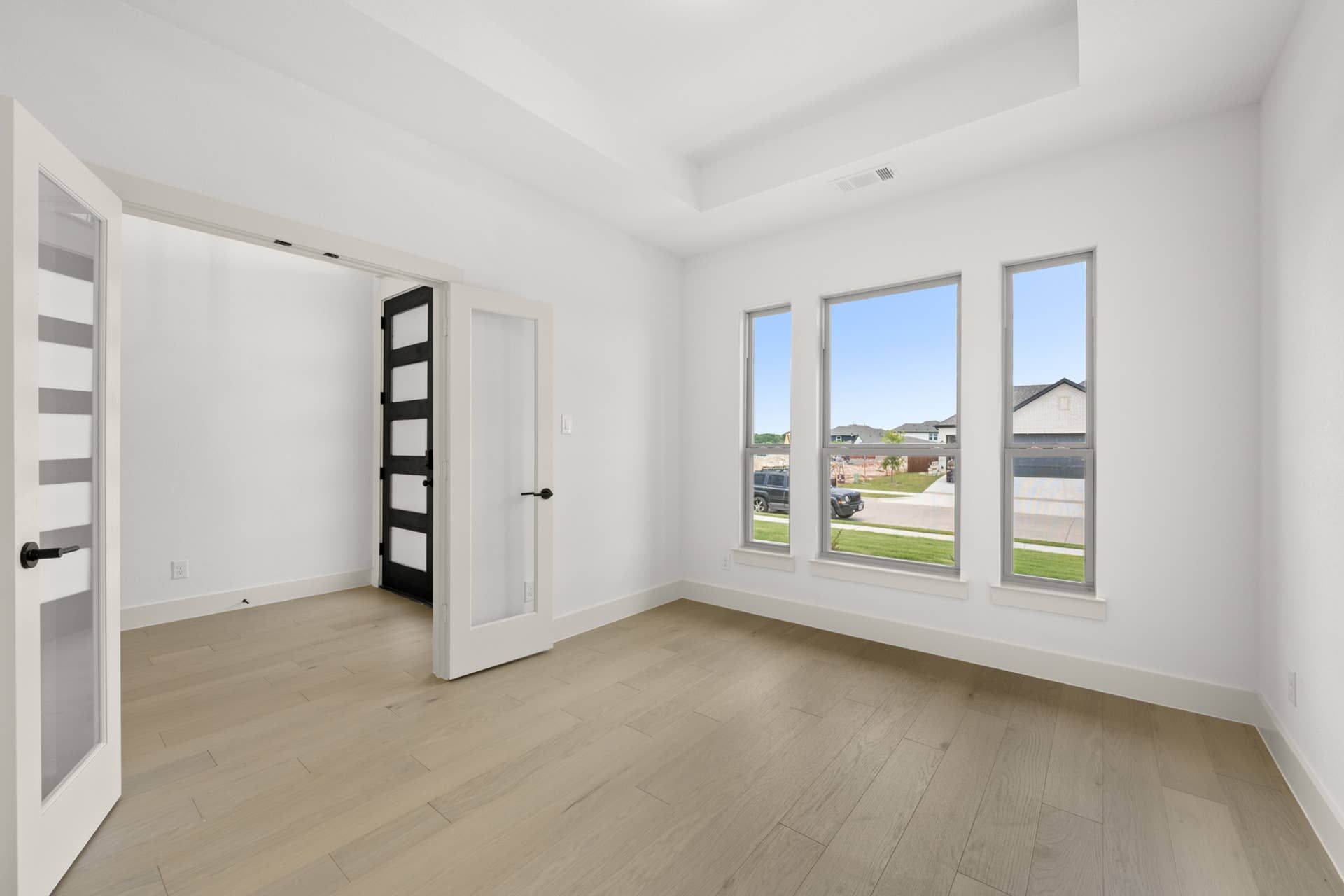 Spacious study room with glass French doors and large windows.