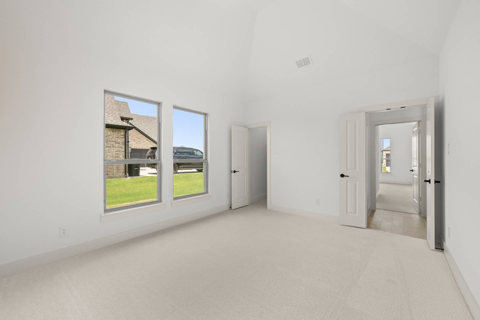 Spacious game room with carpet flooring and large windows for natural light.