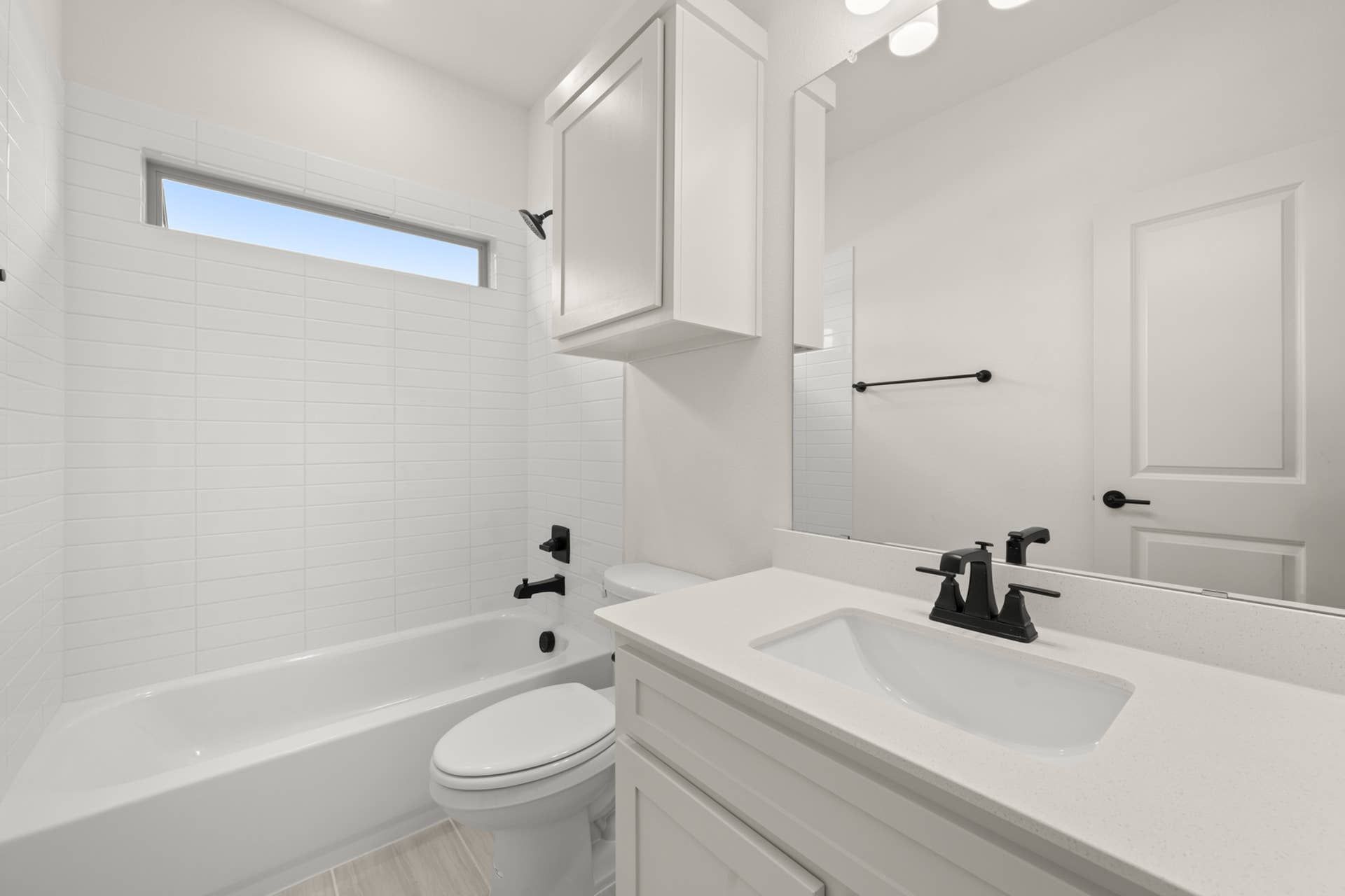 Modern bathroom with white tiles, sleek fixtures, and large mirror.