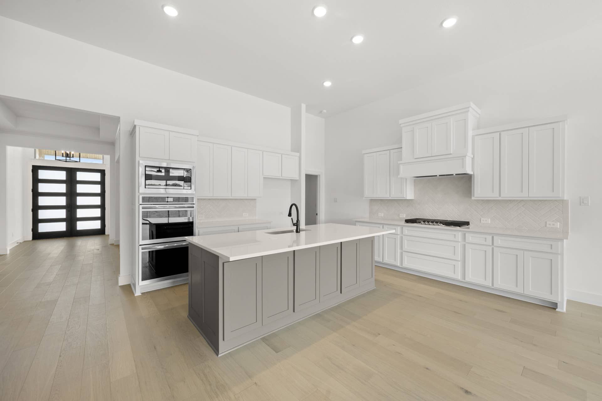 Modern kitchen with white cabinetry, central island, and wood flooring.