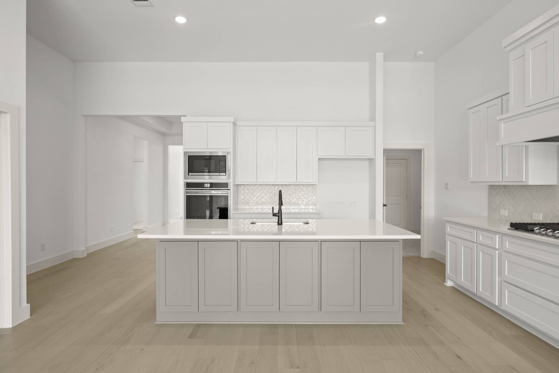 Modern kitchen with white cabinetry, island, and built-in appliances.