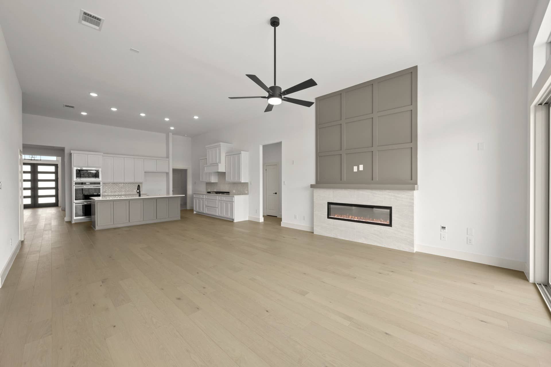 Spacious modern living room with open kitchen and sleek linear fireplace.
