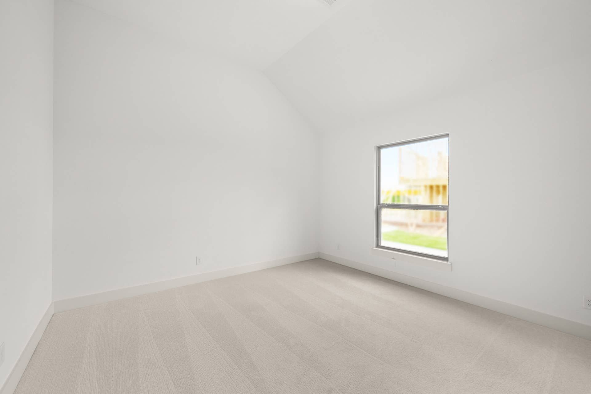 Bright, empty bedroom with carpet and single window.
