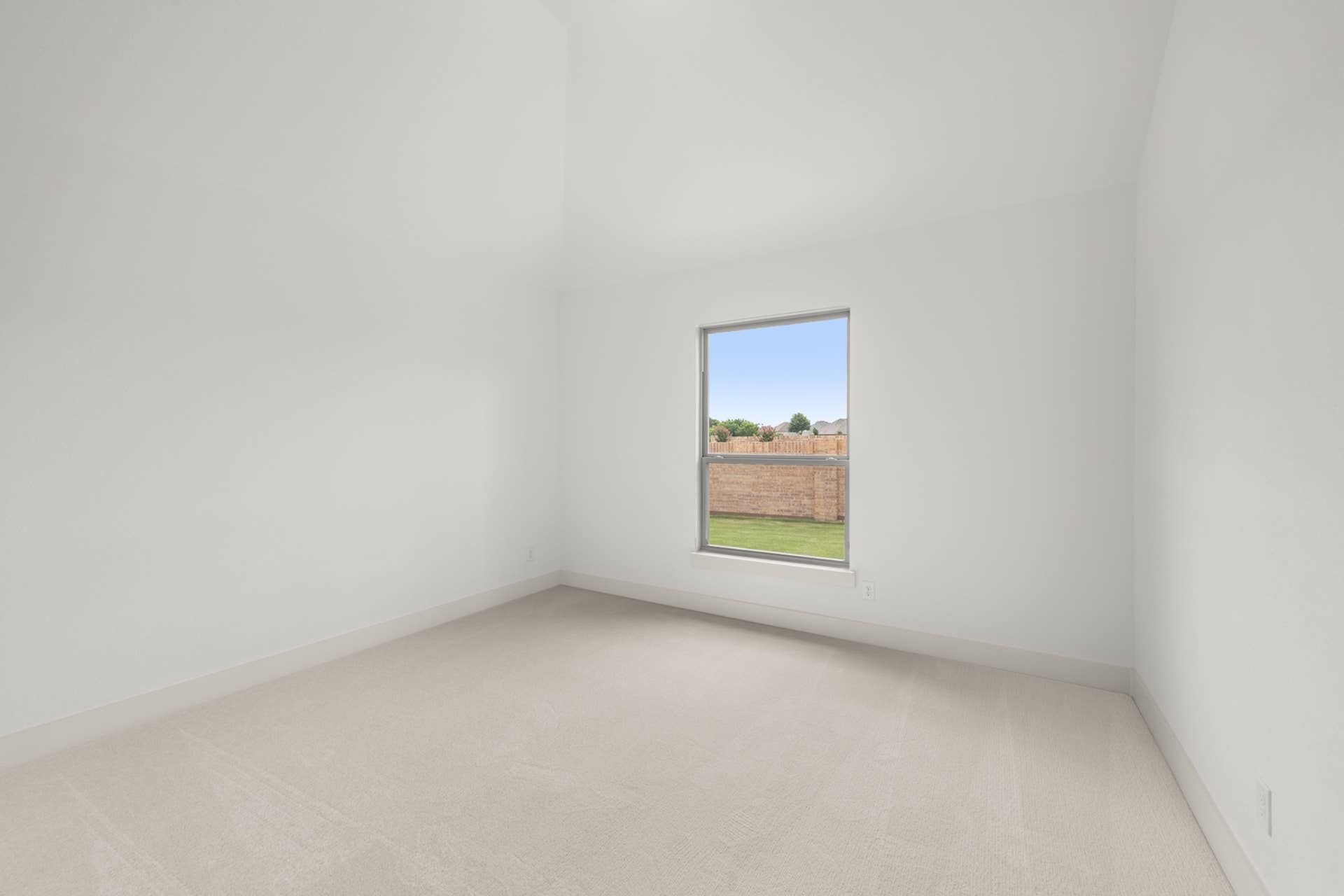 Spacious bedroom with neutral carpet and large window overlooking backyard.