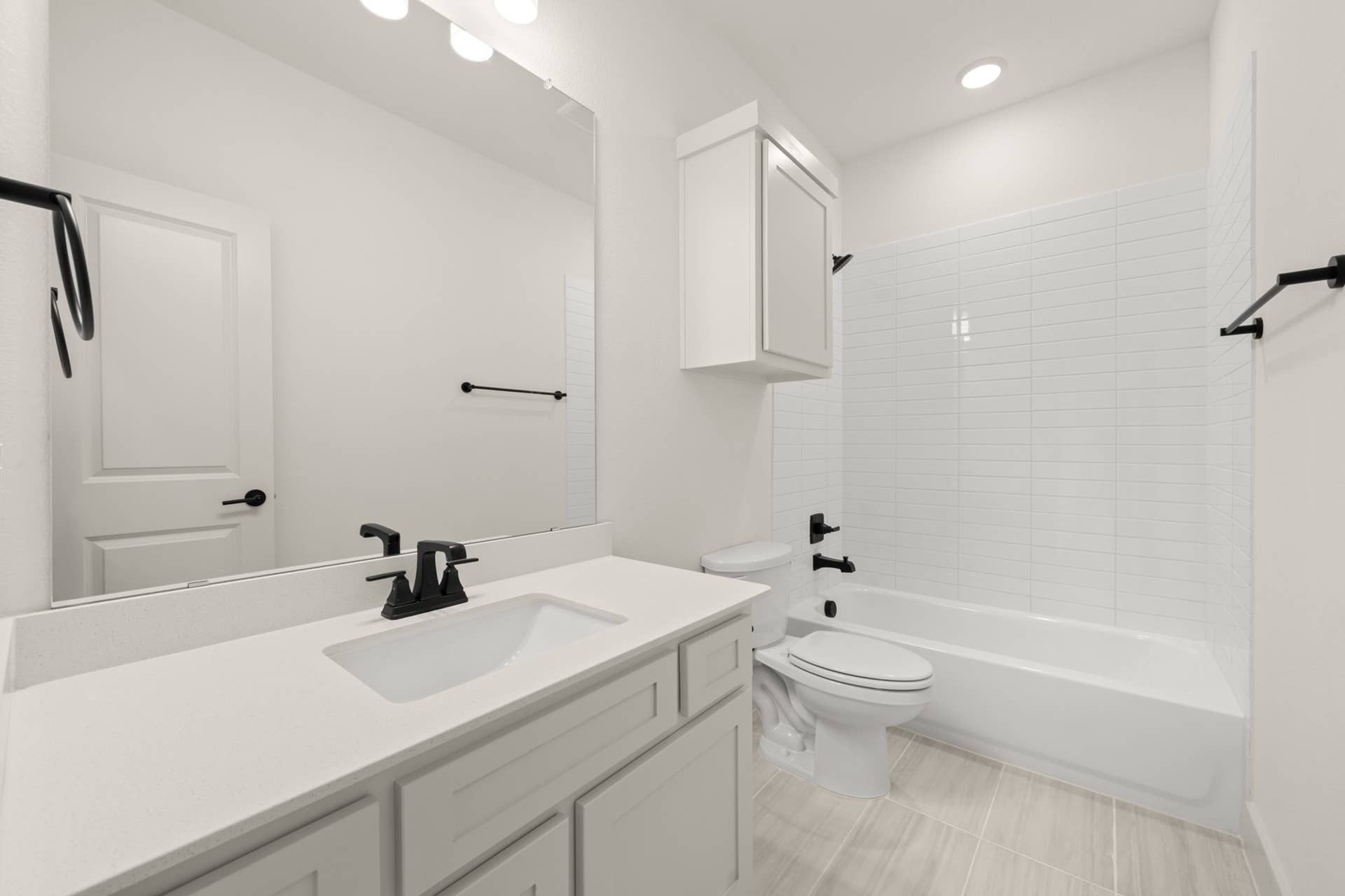 Modern white bathroom with sleek fixtures and large mirror.