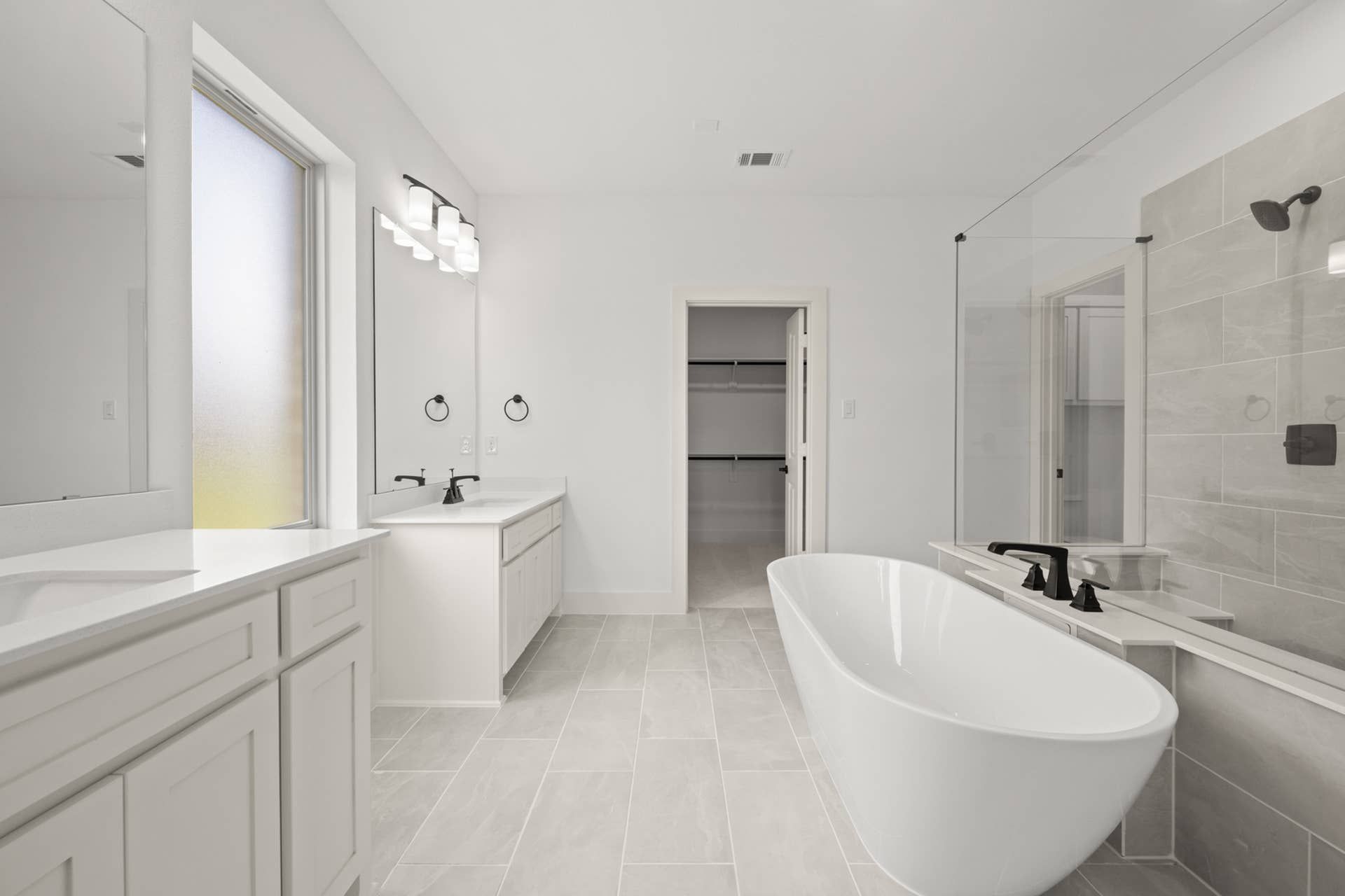 Spacious modern bathroom with freestanding tub, dual vanities, and walk-in closet.