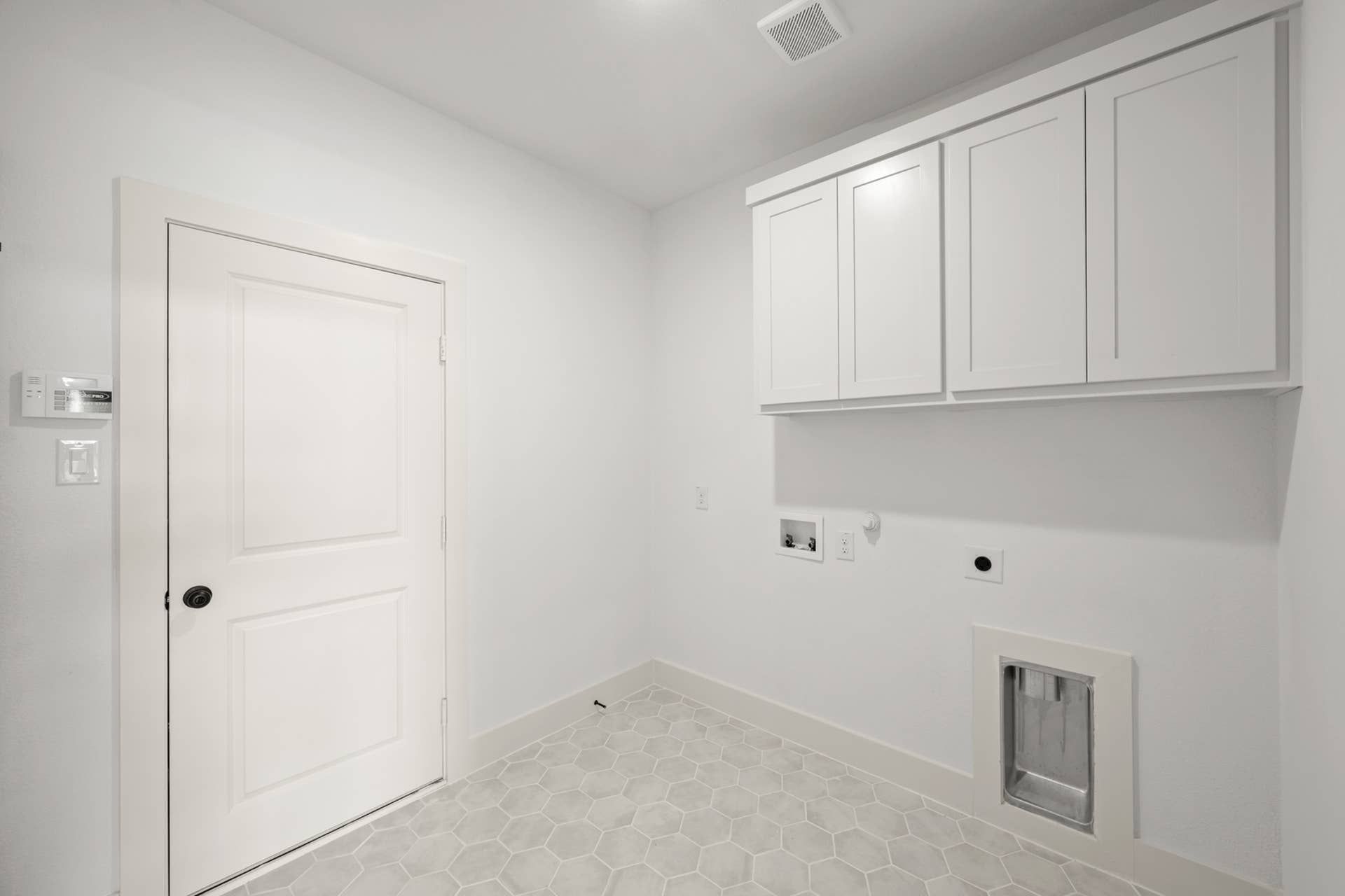 Modern utility room with white cabinetry and hexagonal tile flooring.