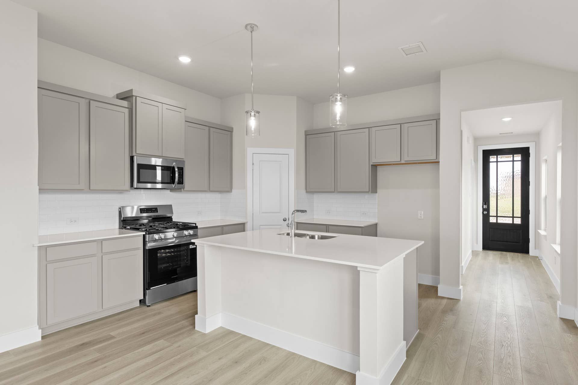 Modern kitchen with gray cabinets, island, and stainless steel appliances.