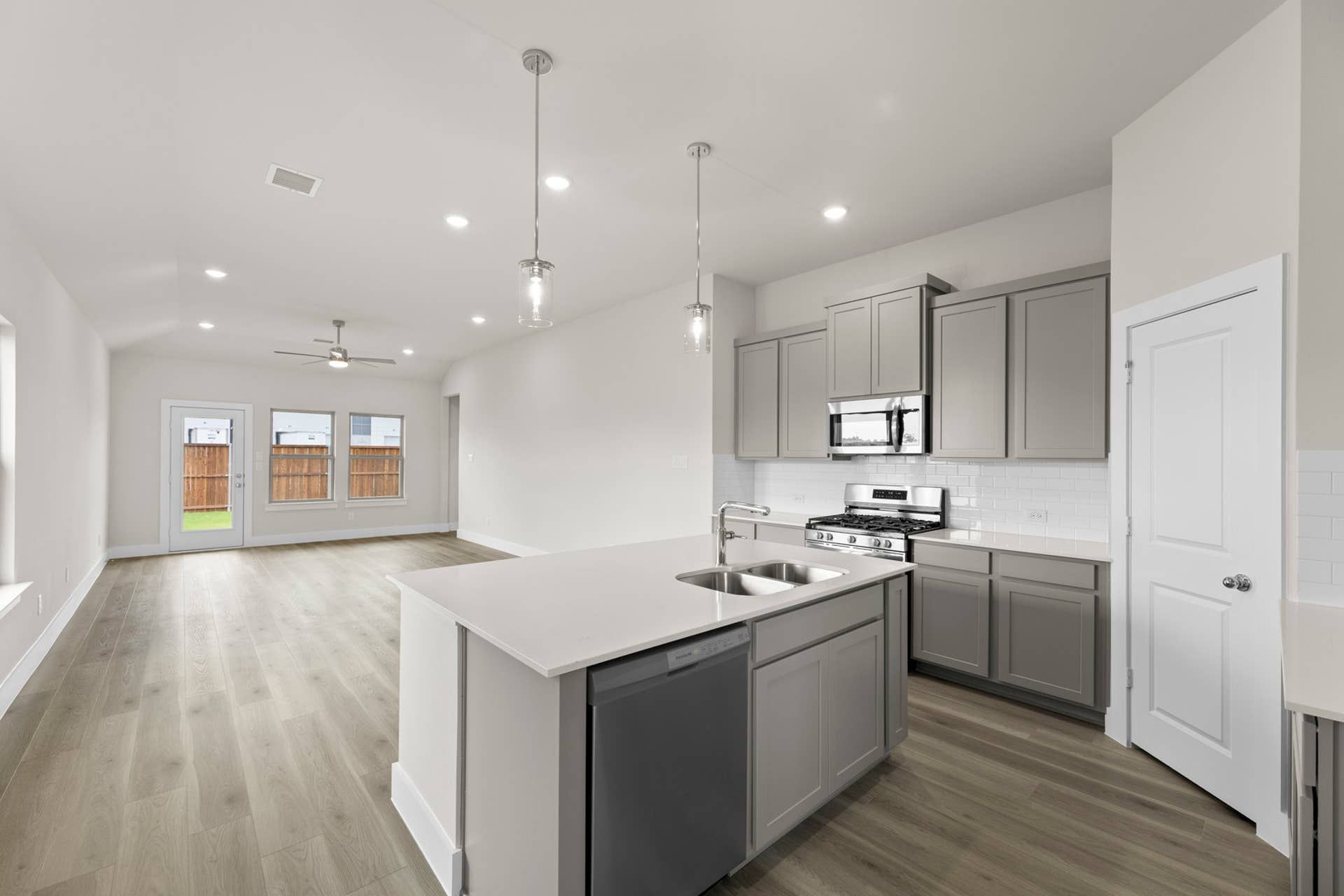 Modern kitchen interior with gray cabinets, island, and open living area.